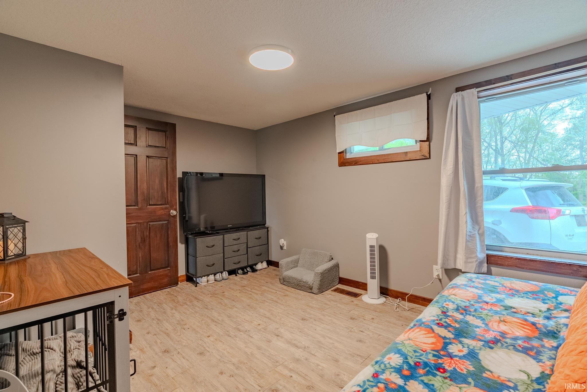 Bedroom featuring light wood-style laminate floors and a textured ceiling
