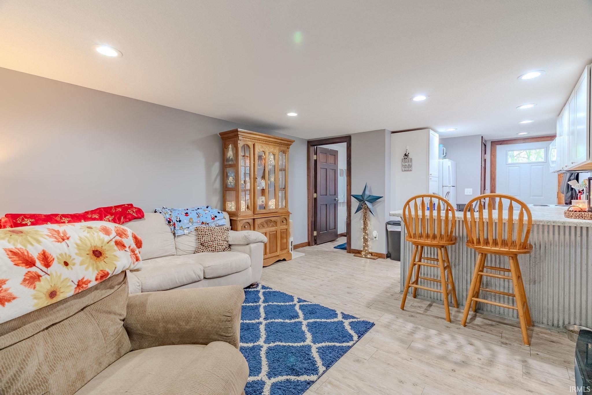 Living area with light laminate flooring, recessed lighting, and bar area