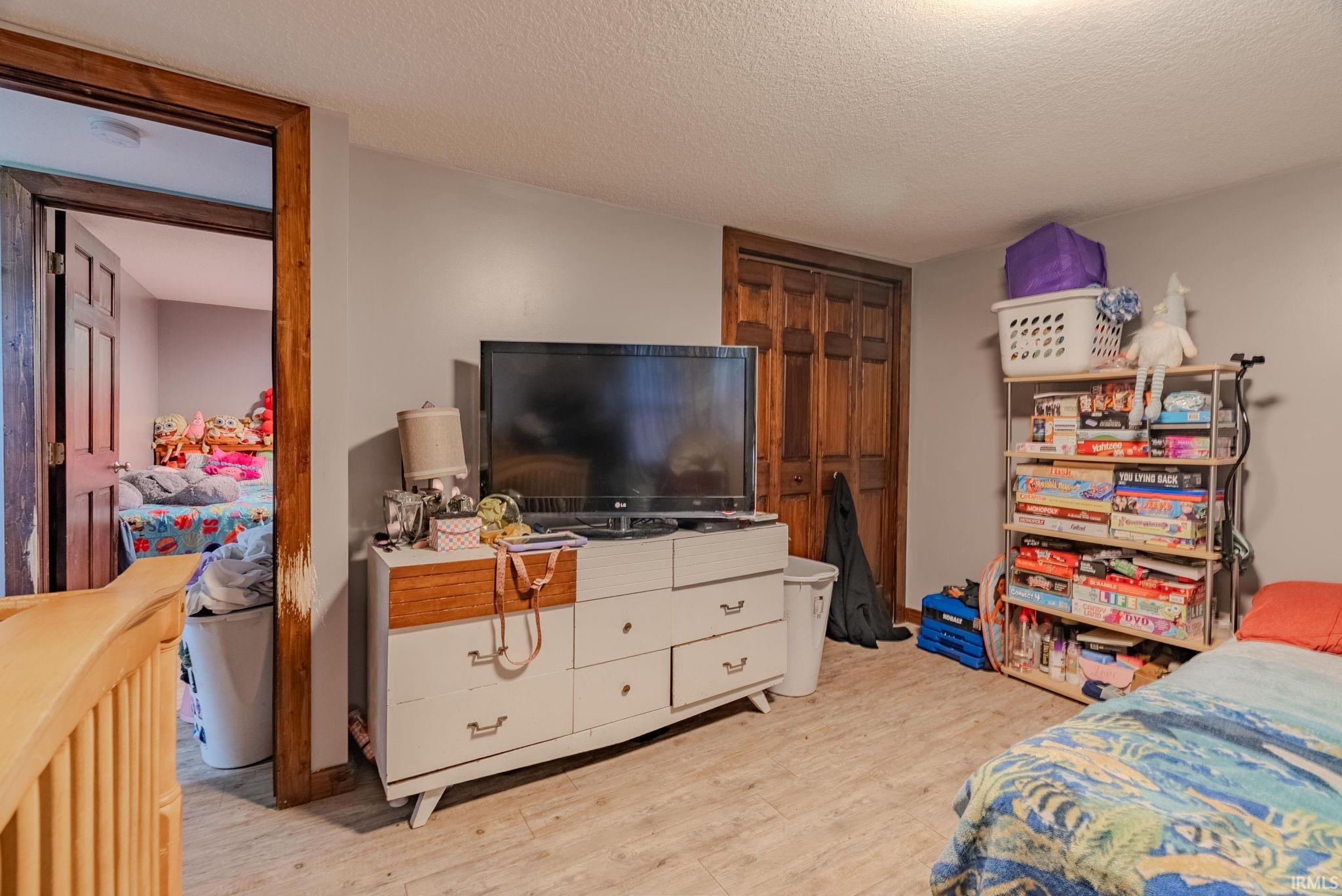 Bedroom featuring a textured ceiling, light wood-type laminate flooring, and a closet