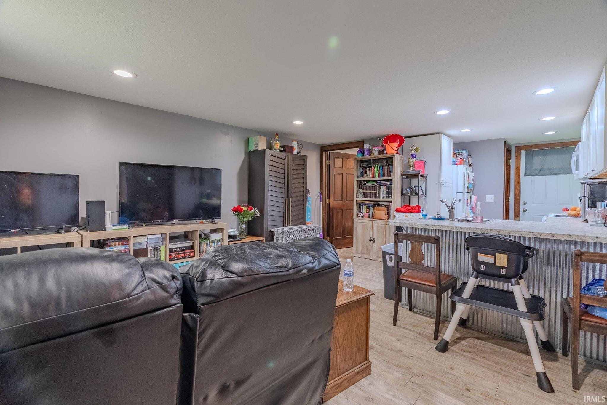 Living room with light wood-style laminate floors and recessed lighting