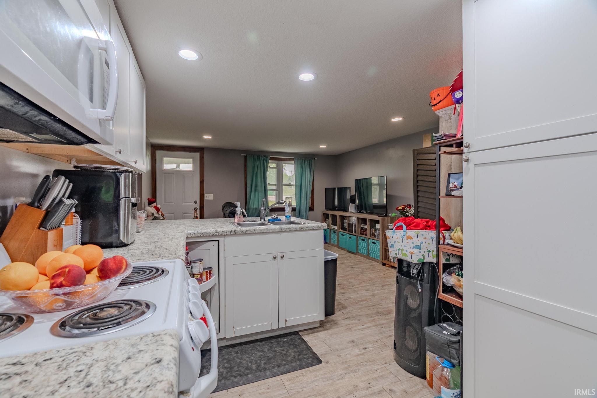 Kitchen featuring a peninsula, white appliances, white cabinets, light countertops, and recessed lighting