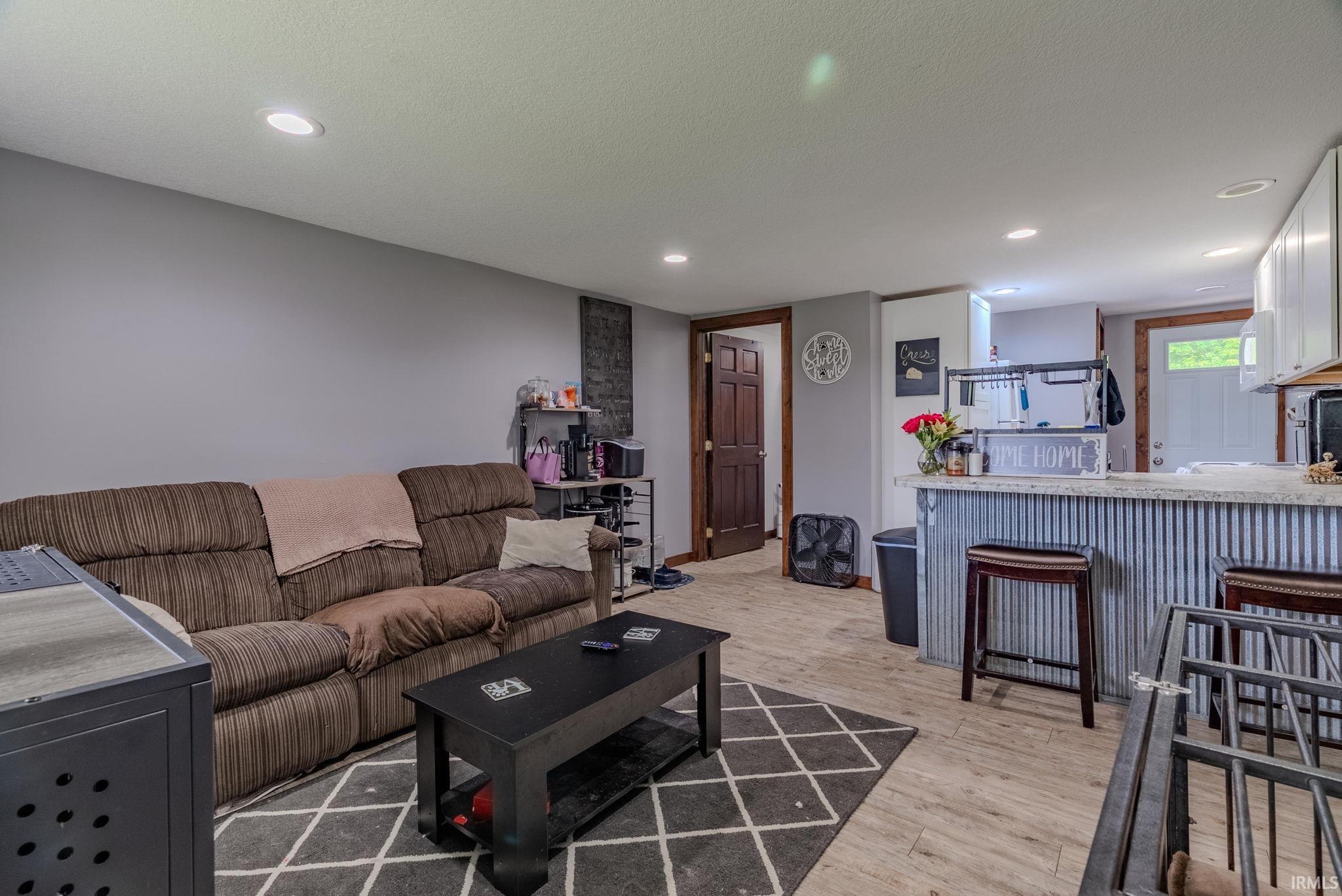 Living area with light wood-style laminate floors and recessed lighting