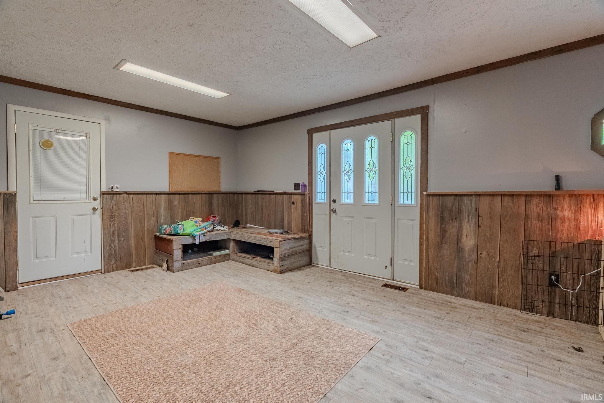 mud room with a wood wall, laminate floors, and a textured ceiling