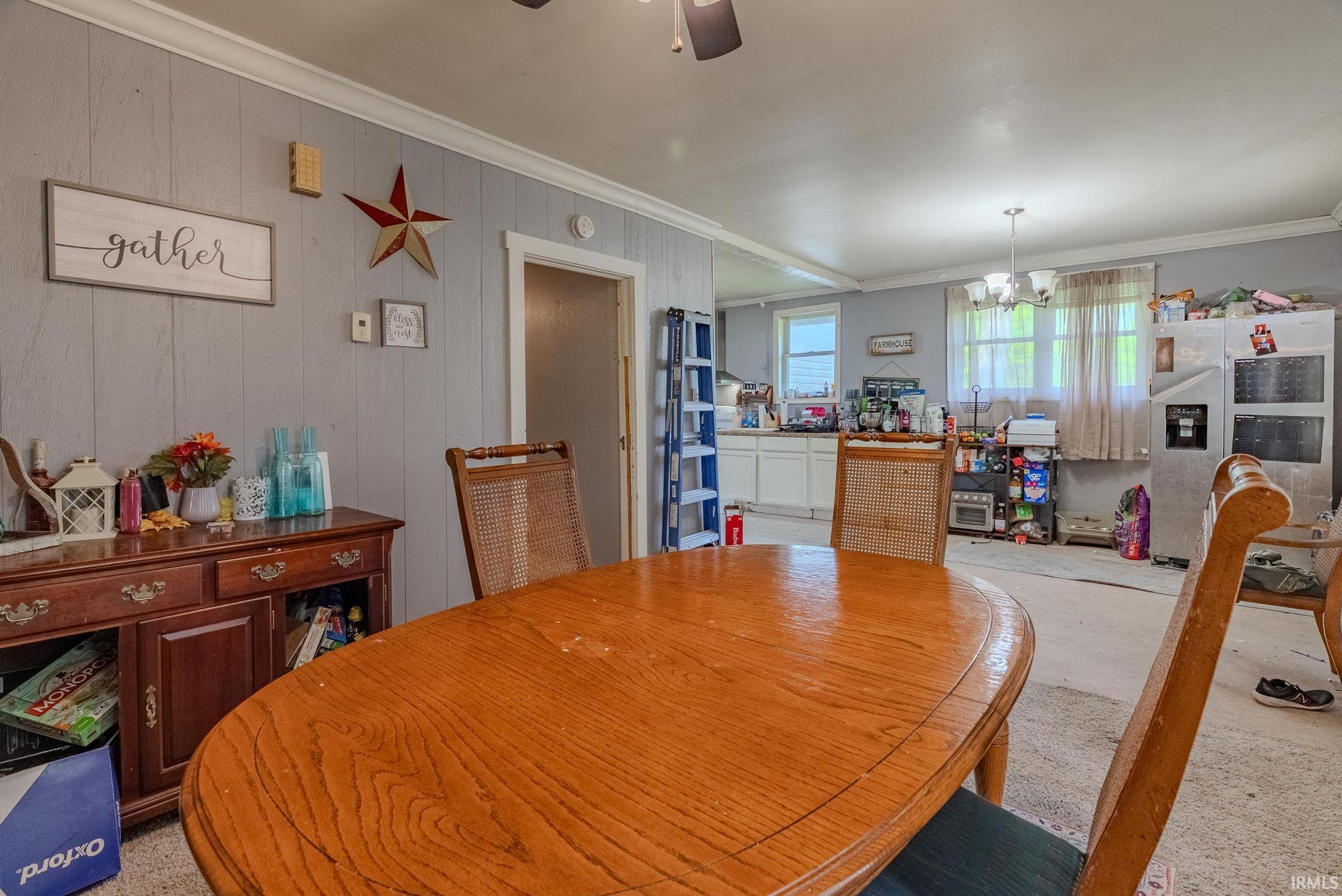 Dining space featuring ornamental molding, ceiling fan, panel wooden walls