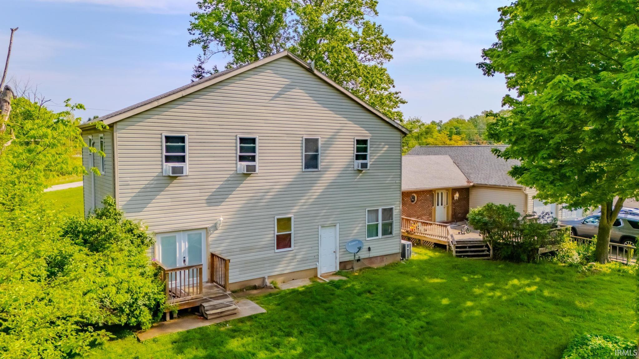 Rear view of house with a lawn and a wooden deck