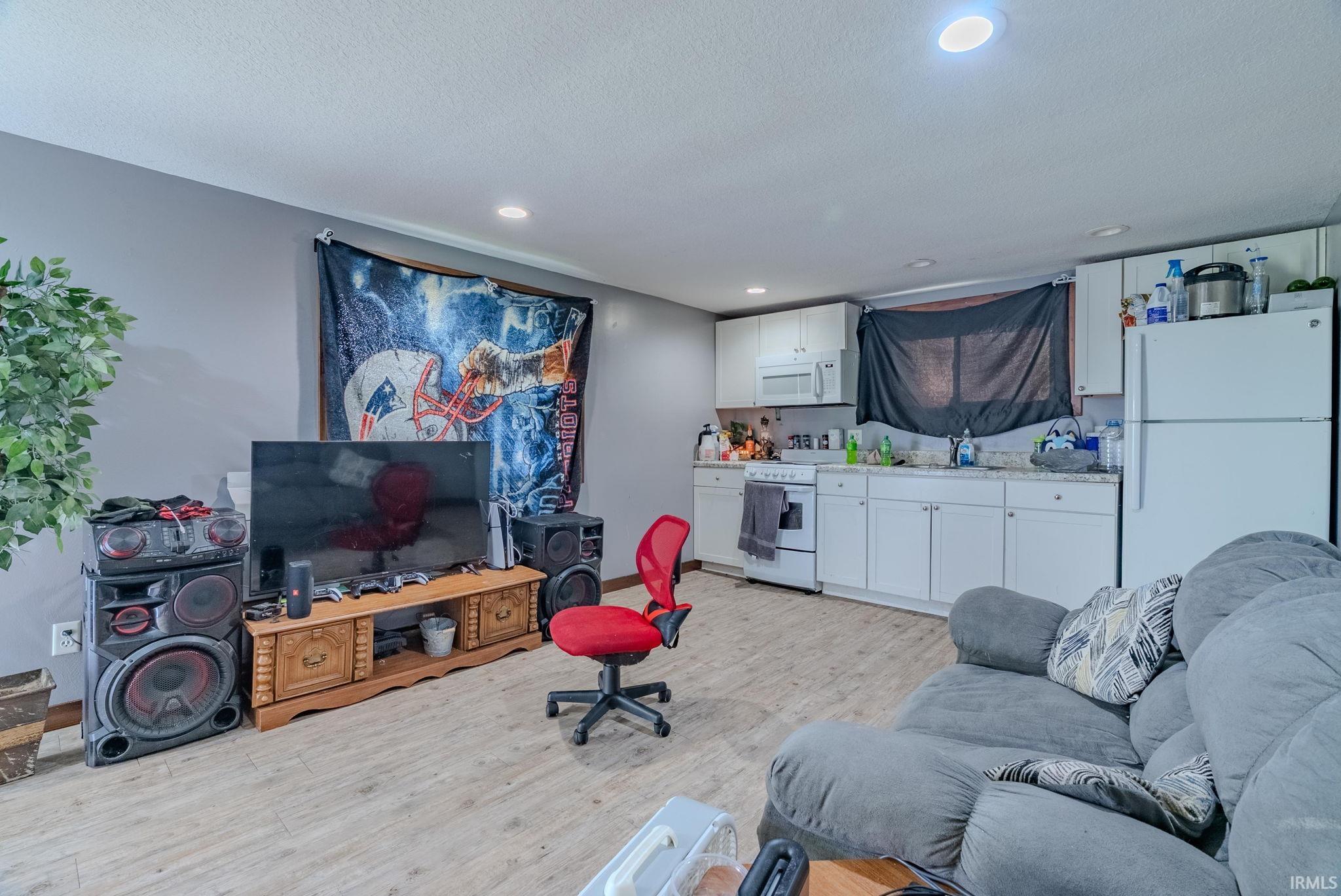 Living area with light laminate flooring, recessed lighting, and a textured ceiling