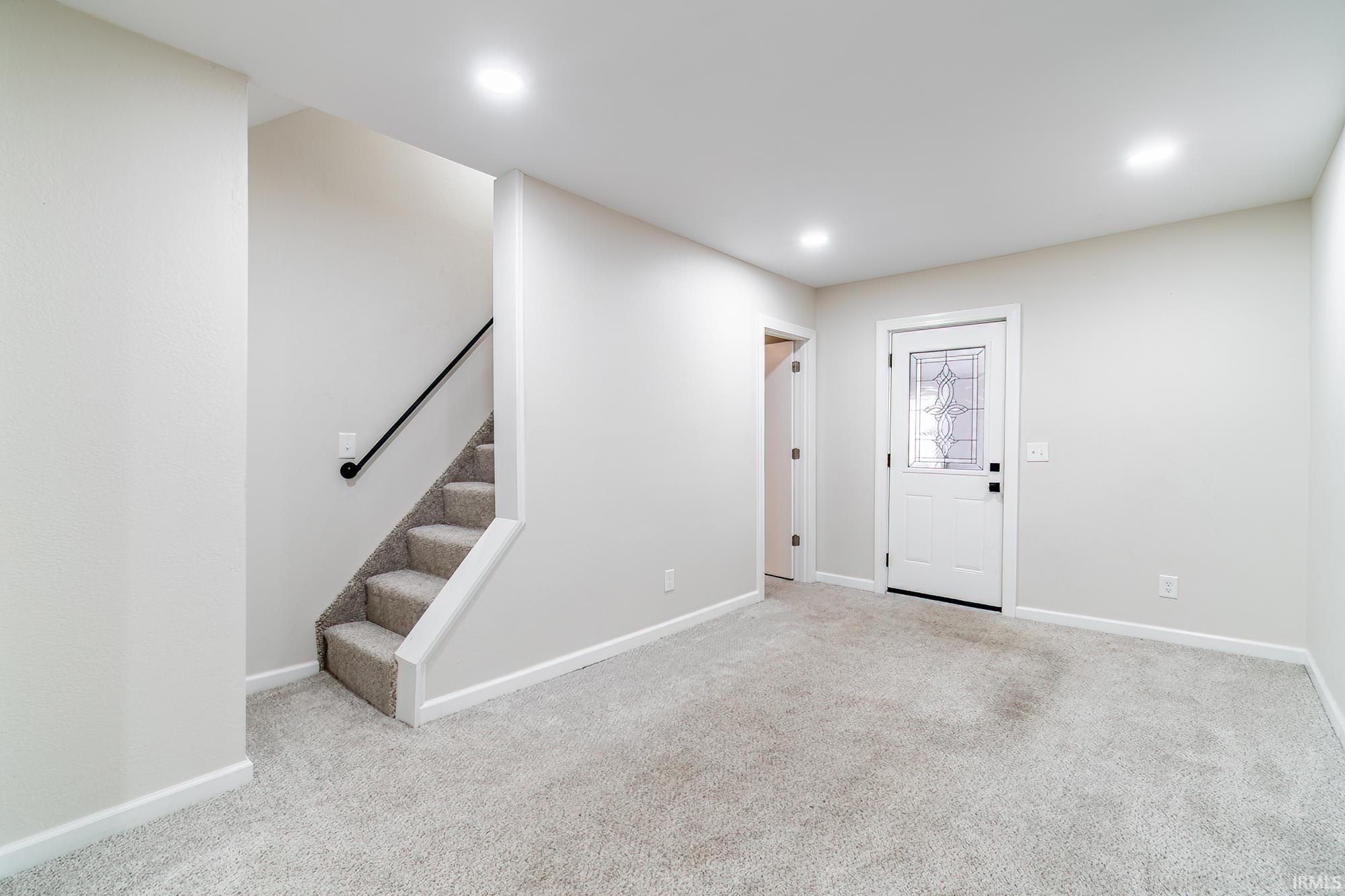 Entryway featuring stairs, light colored carpet, and recessed lighting