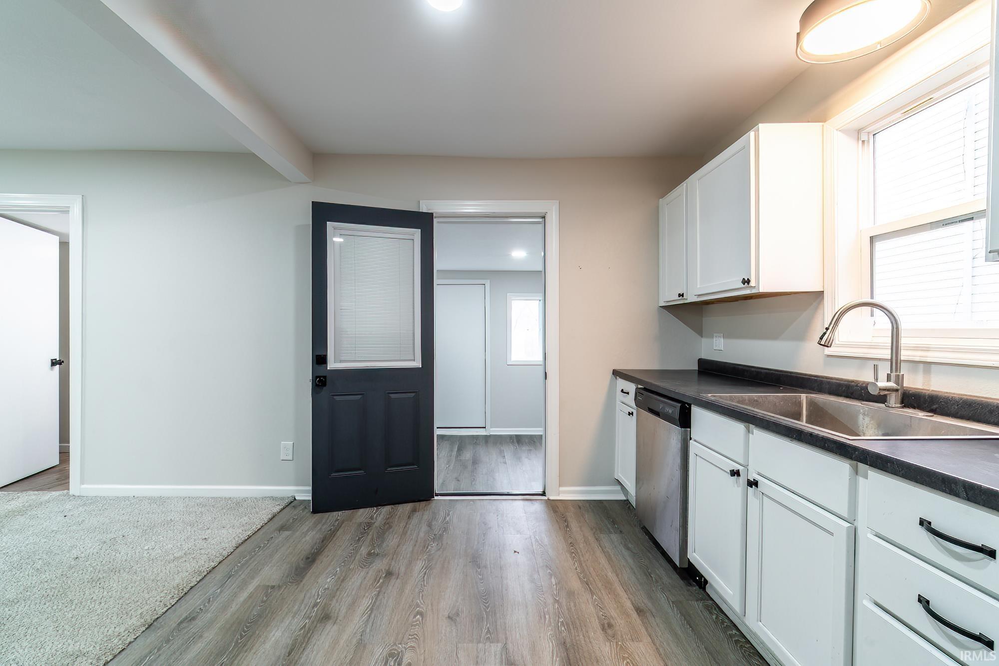 Kitchen featuring dark countertops, white cabinets, light wood finished floors, and dishwasher