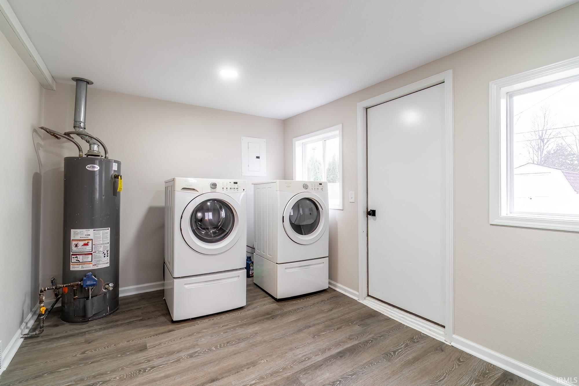 Laundry area with gas water heater, washer and dryer, and wood finished floors