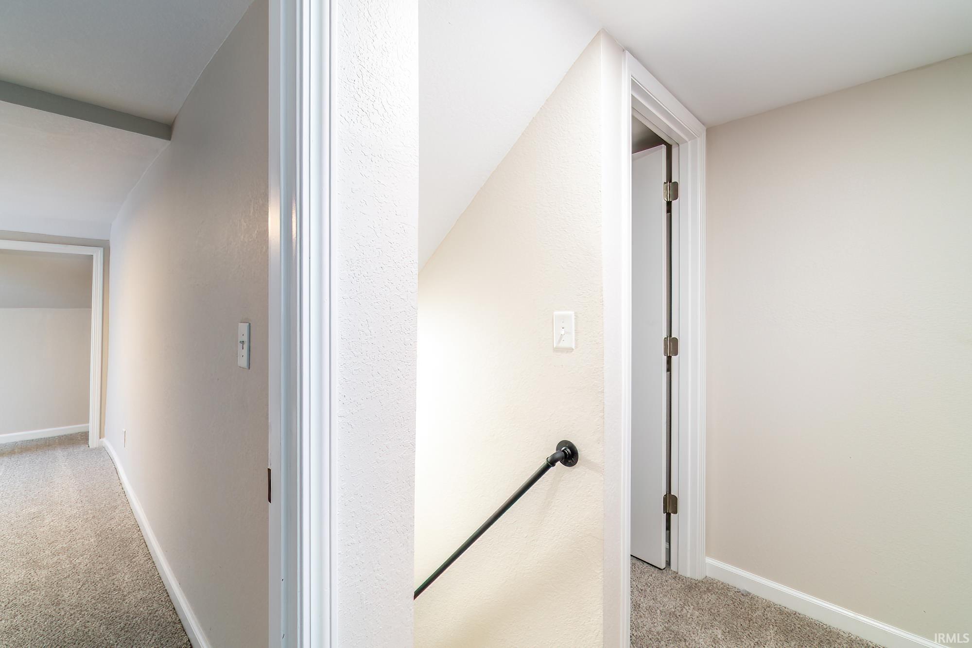 Hallway with light carpet and an upstairs landing
