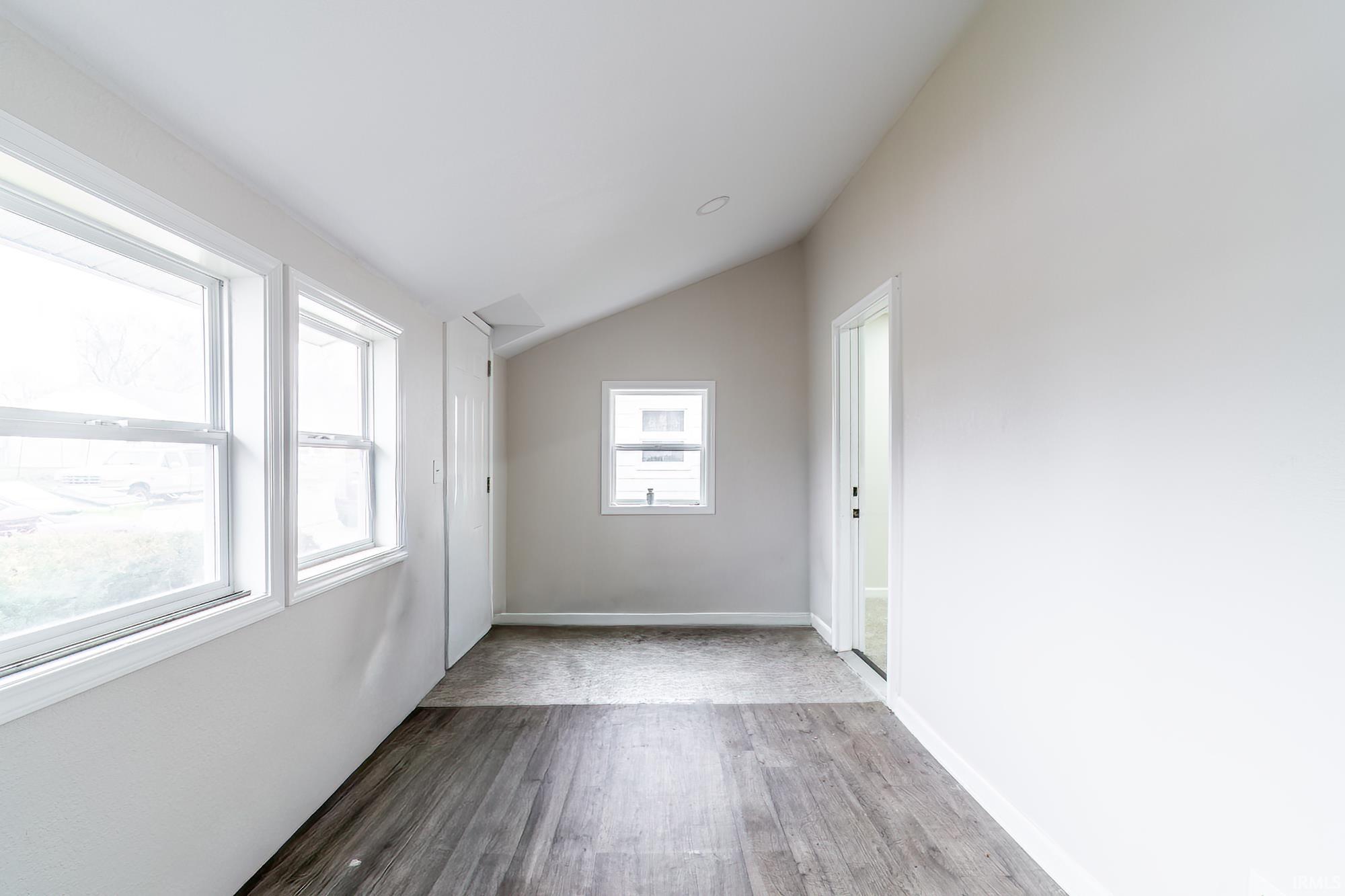 Unfurnished room with lofted ceiling and wood finished floors