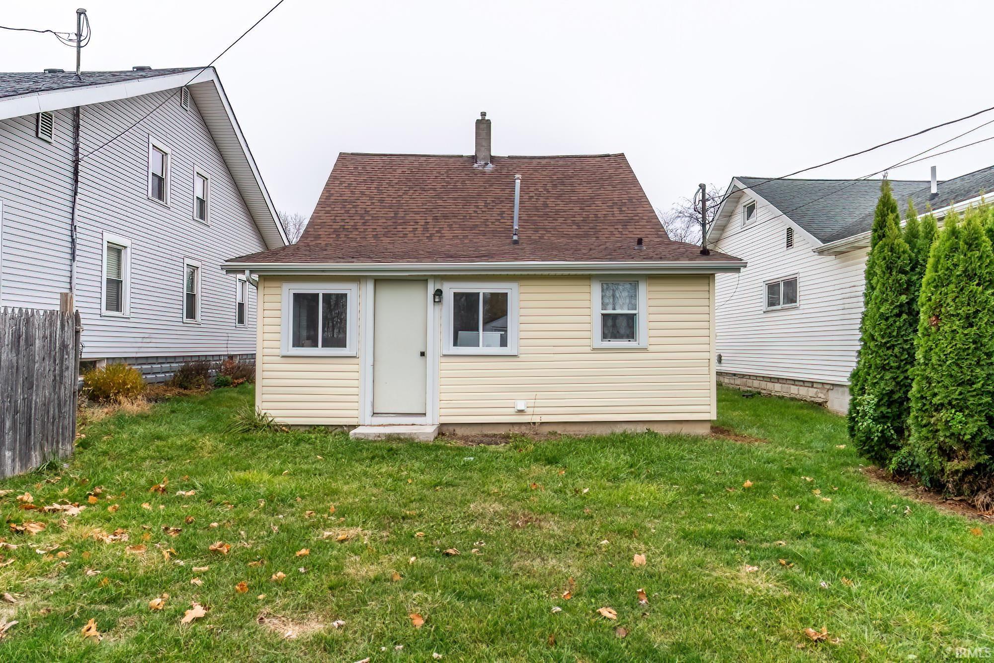 Rear view of house featuring a lawn, a chimney, and a shingled roof