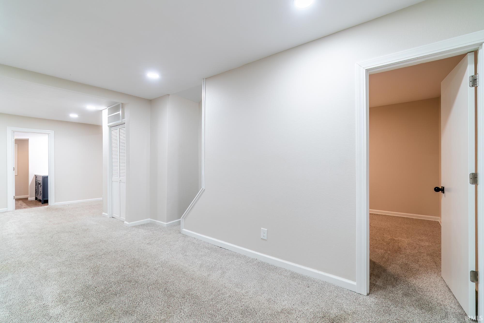 Below grade area with light colored carpet and recessed lighting