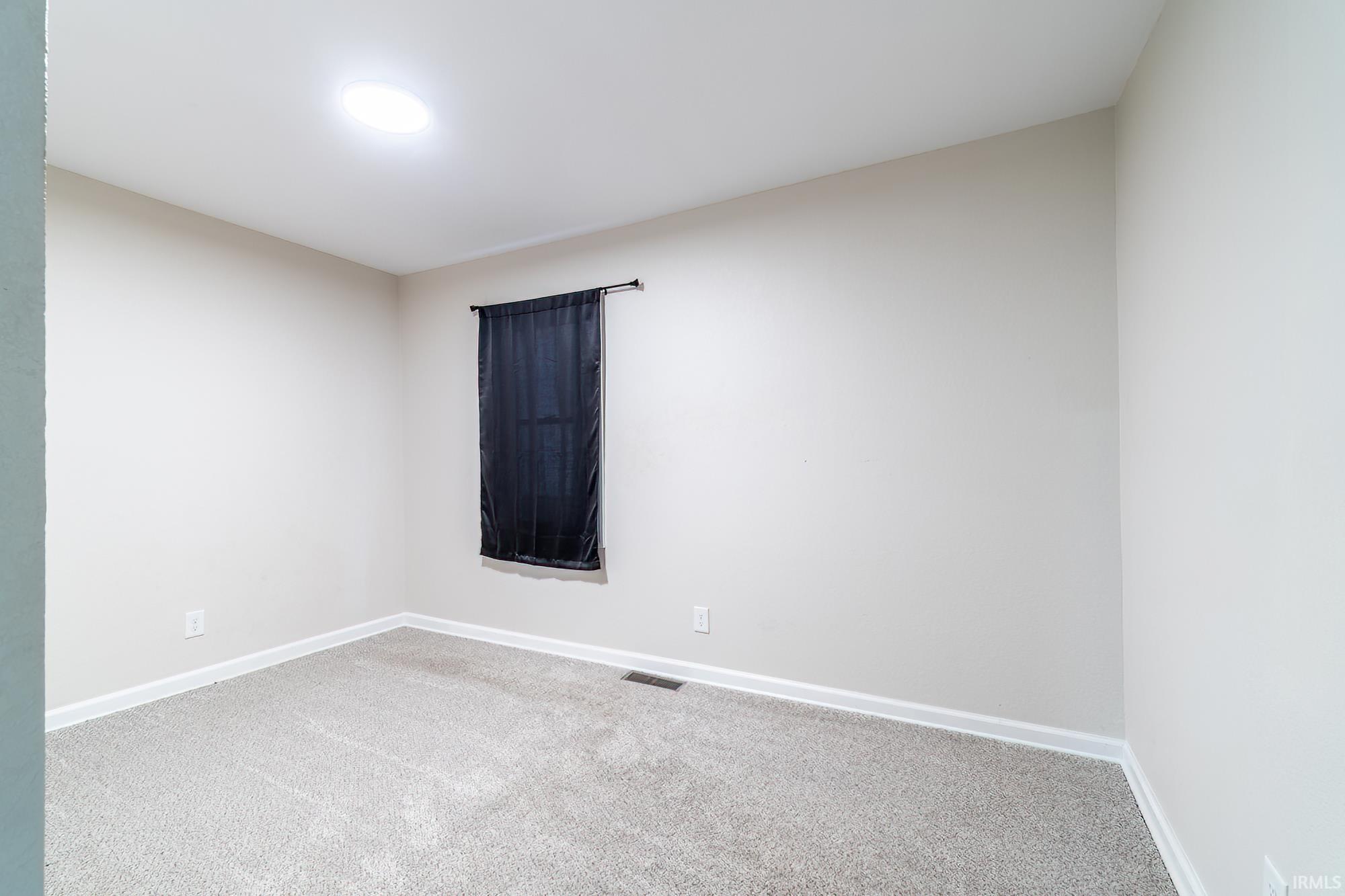 Carpeted spare room with baseboards