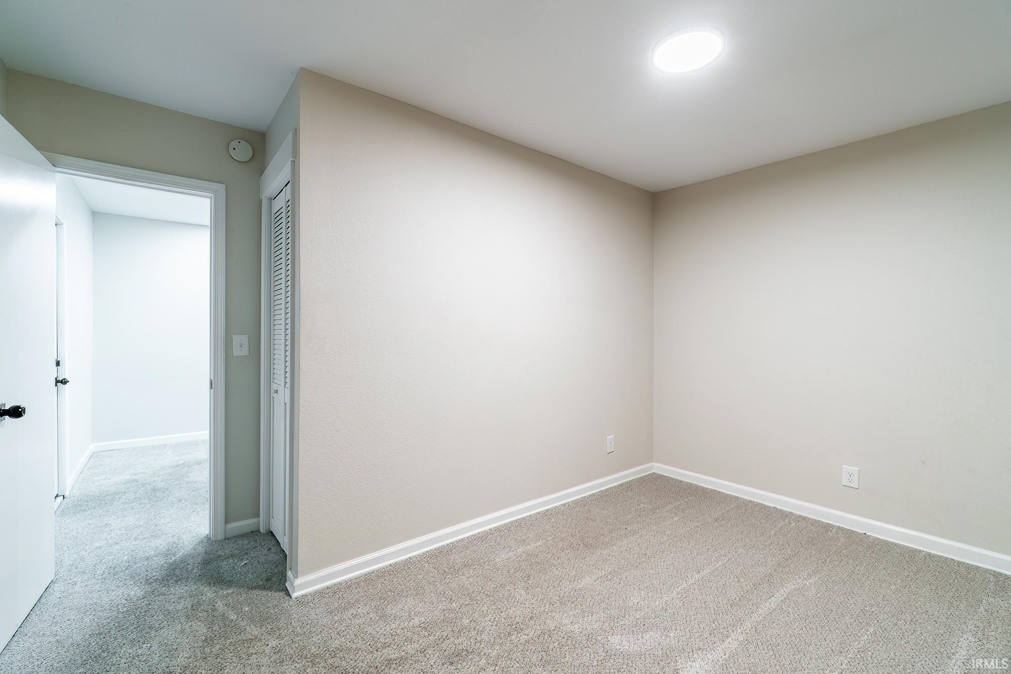 Empty room with light carpet and baseboards