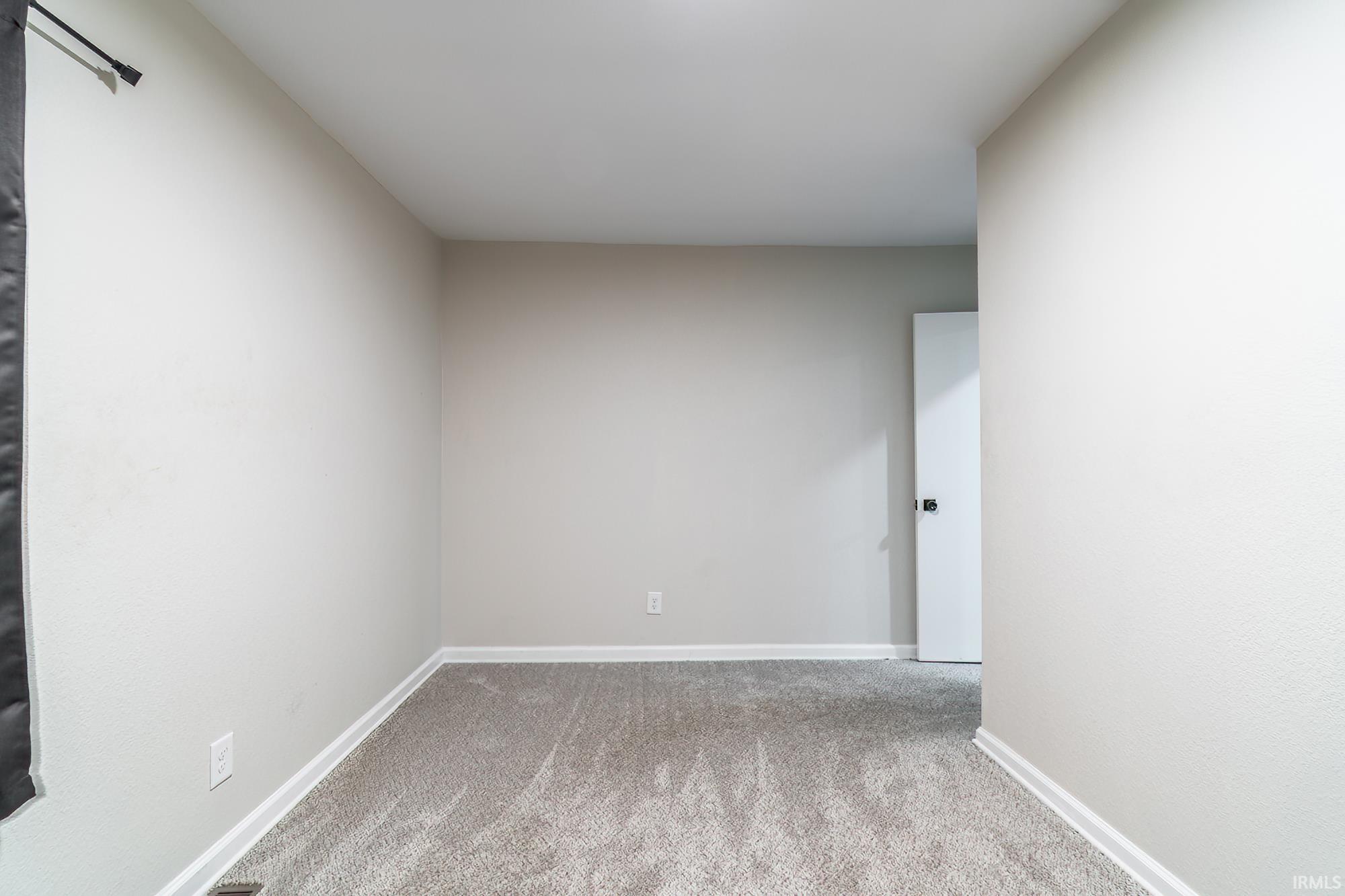 Unfurnished room featuring light carpet and baseboards