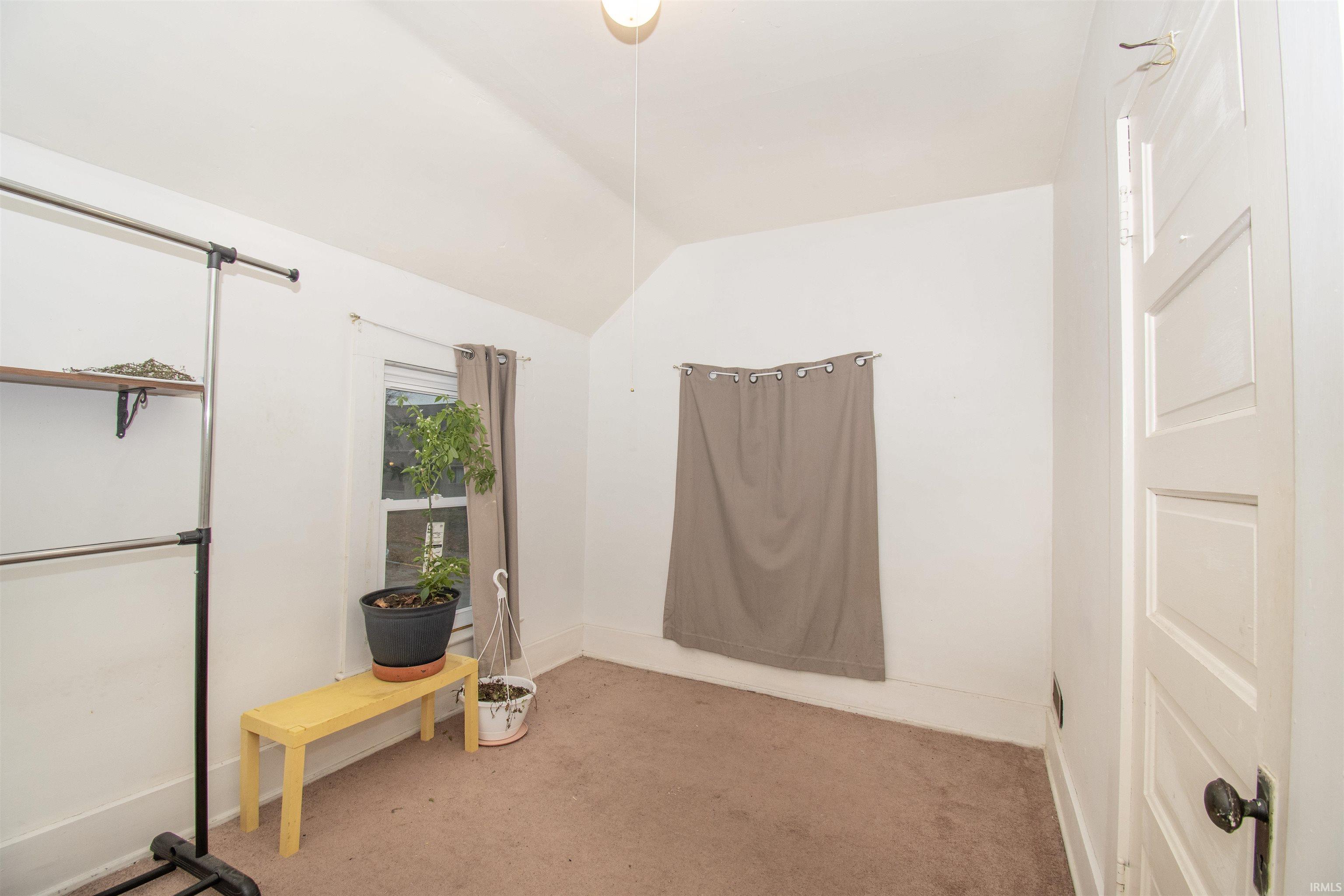Unfurnished bedroom with vaulted ceiling and carpet floors