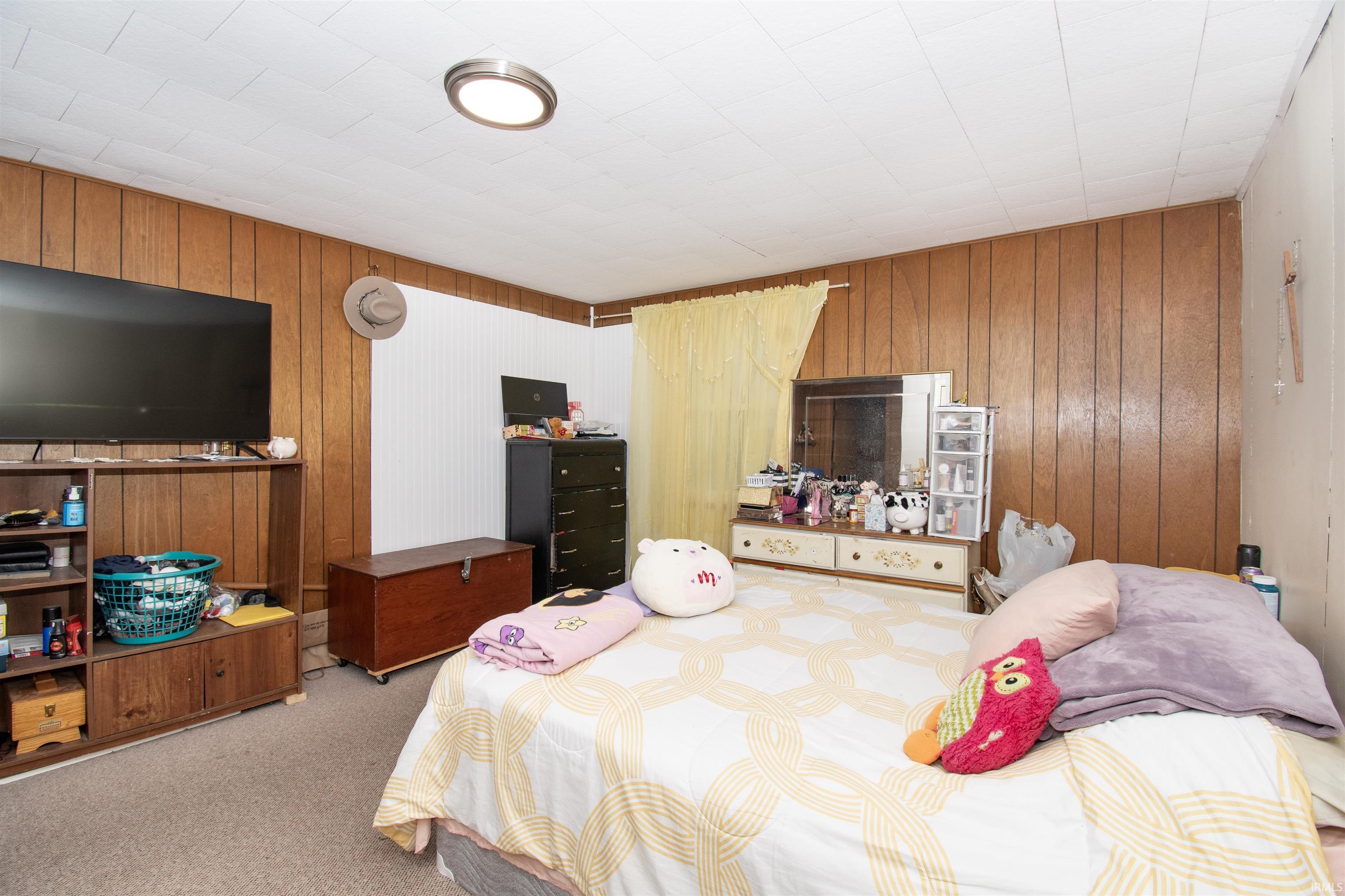 Carpeted bedroom with wood walls