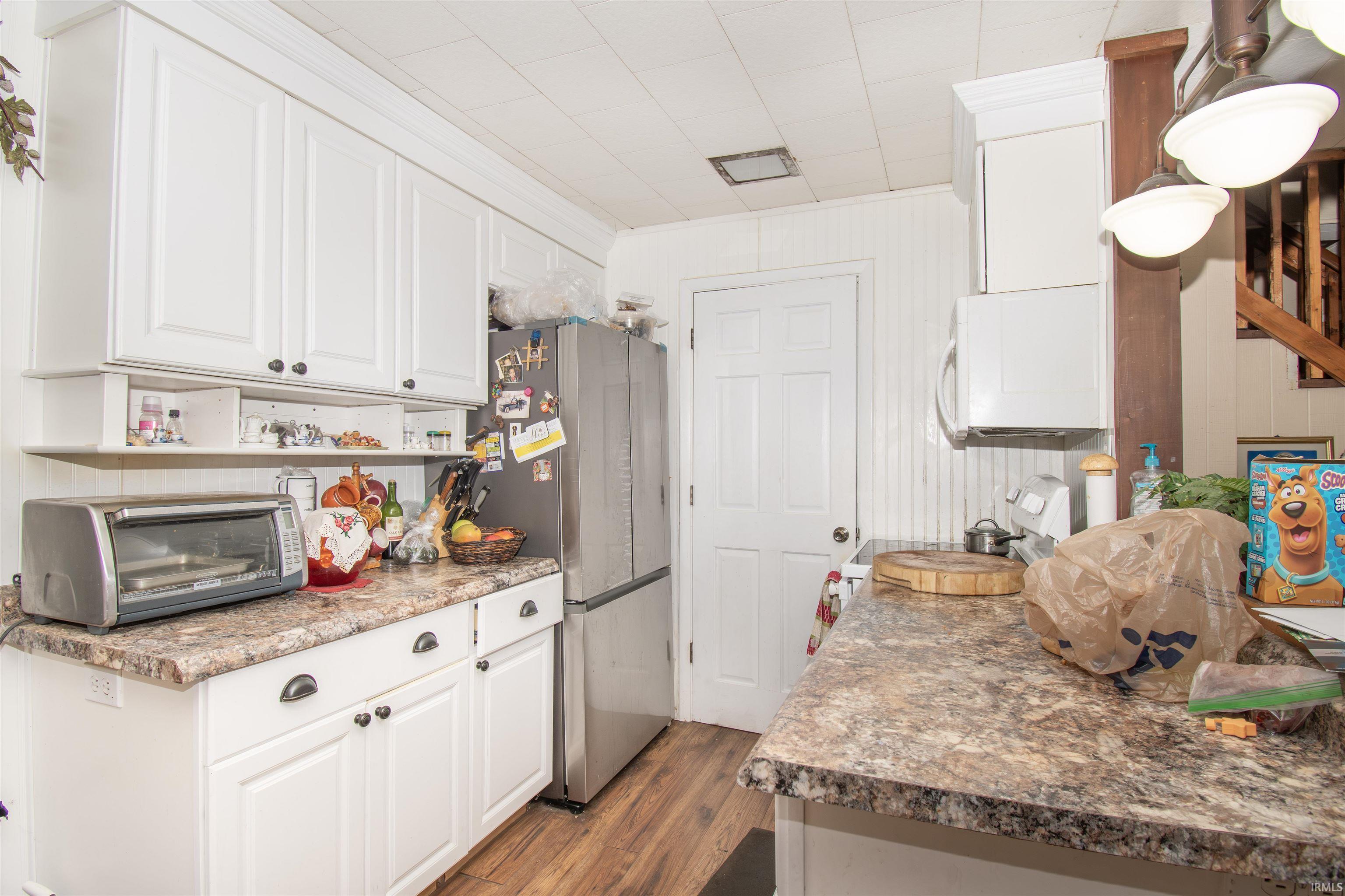 Kitchen with white cabinetry, freestanding refrigerator, dark wood finished floors, and range