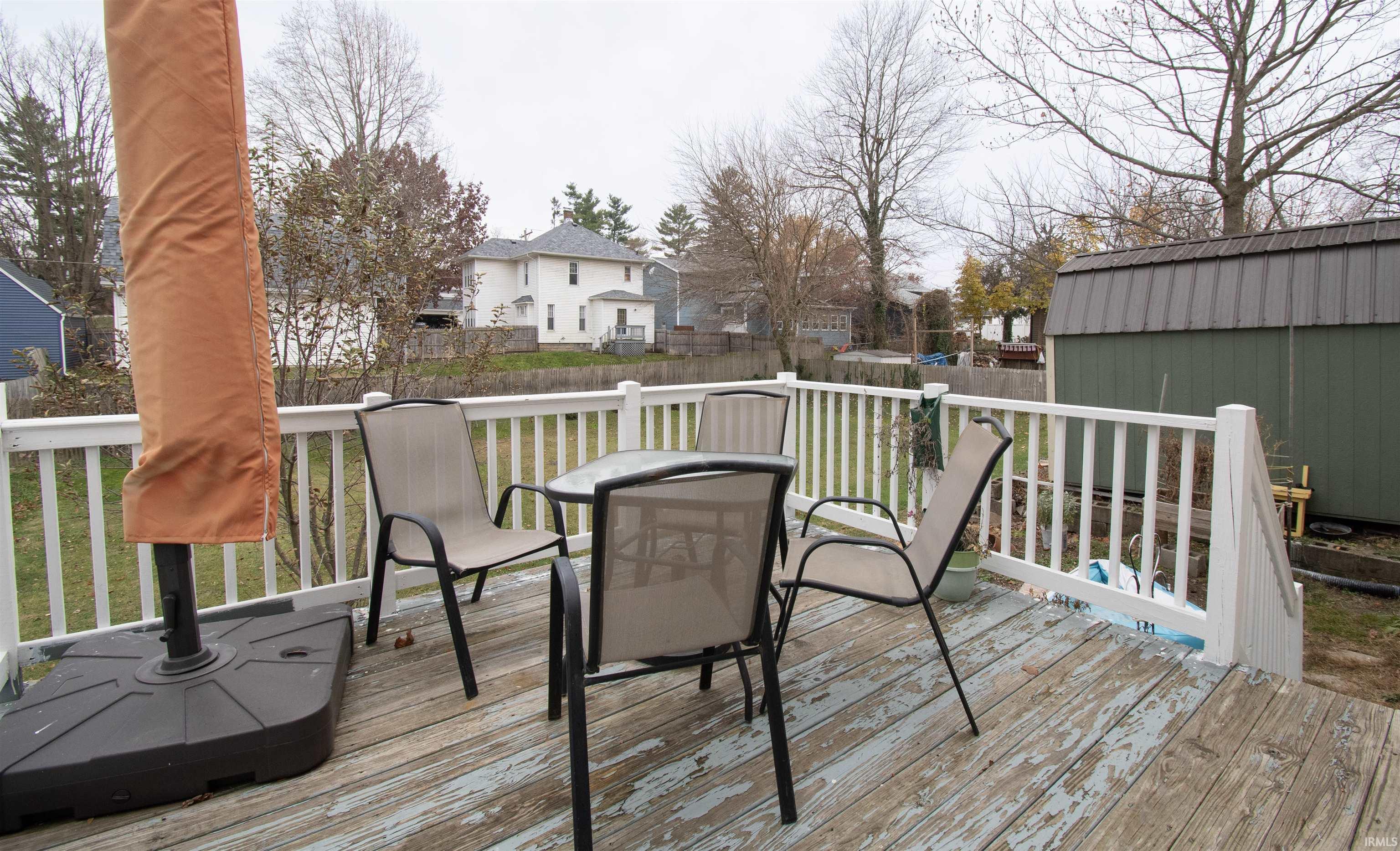 Deck with a fenced backyard, a shed, outdoor dining area, and a trampoline