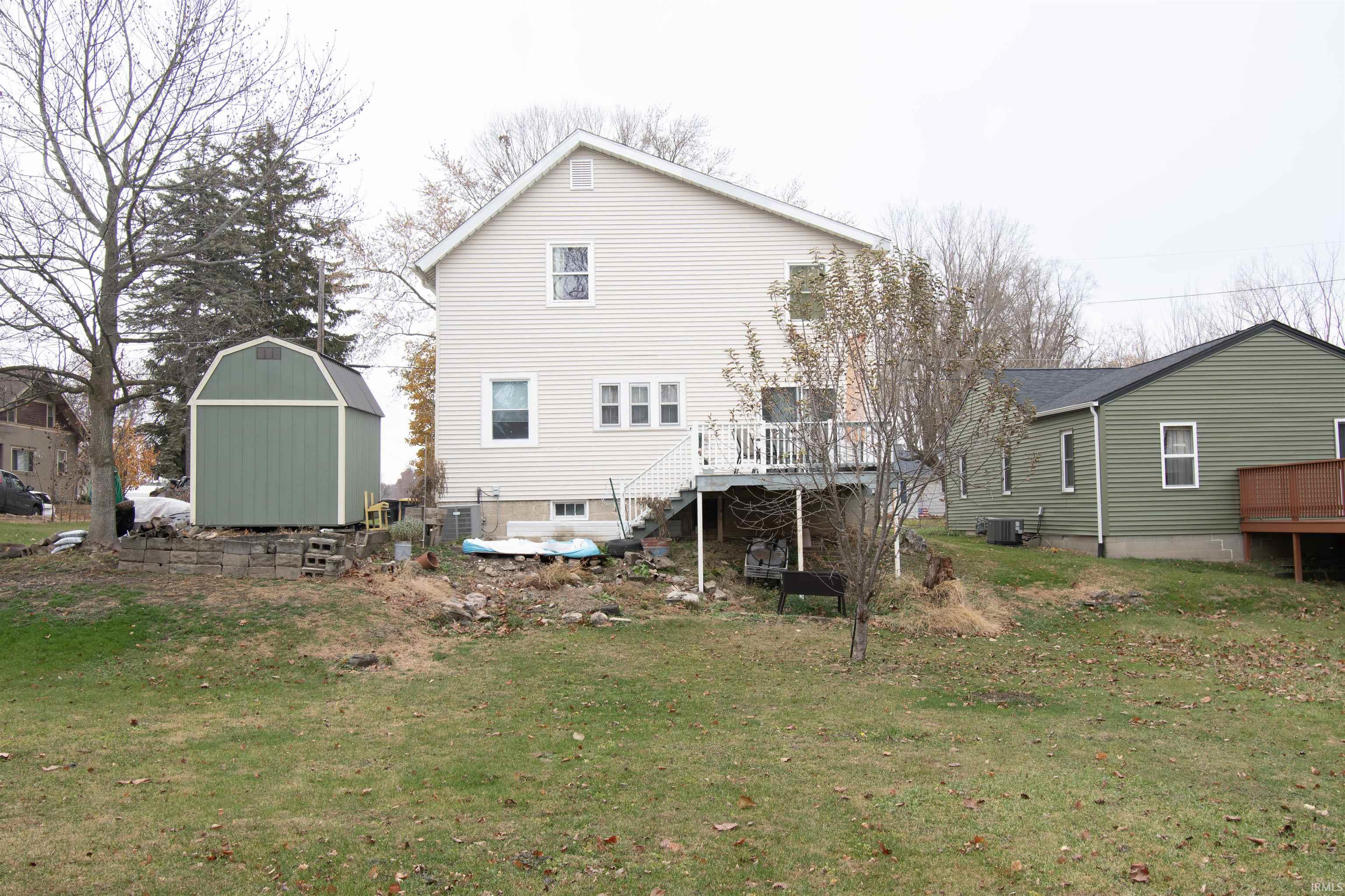 Back of house with a deck, a yard, and a shed