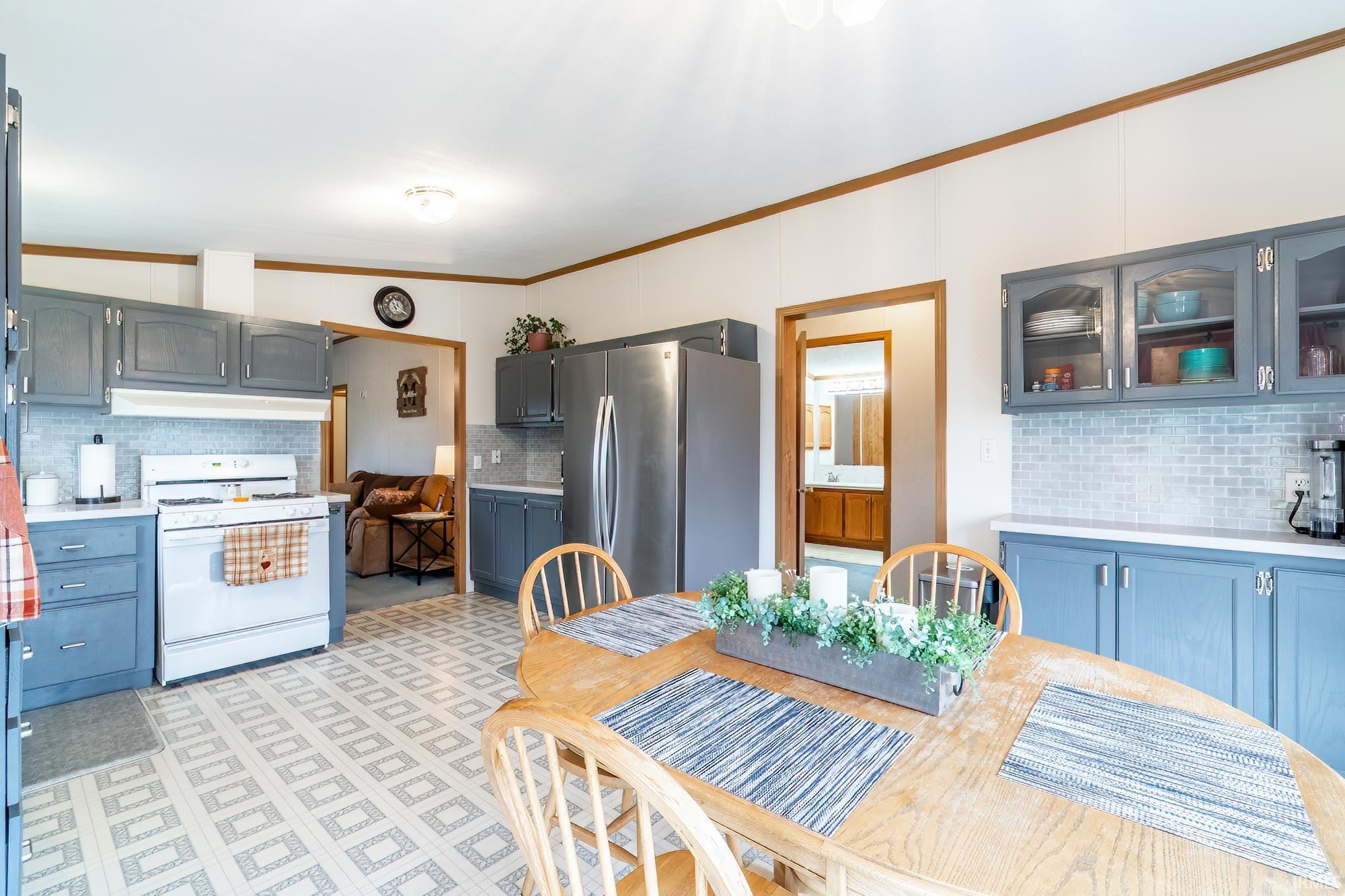 Kitchen featuring decorative backsplash, white gas stove, light countertops, freestanding refrigerator, and crown molding