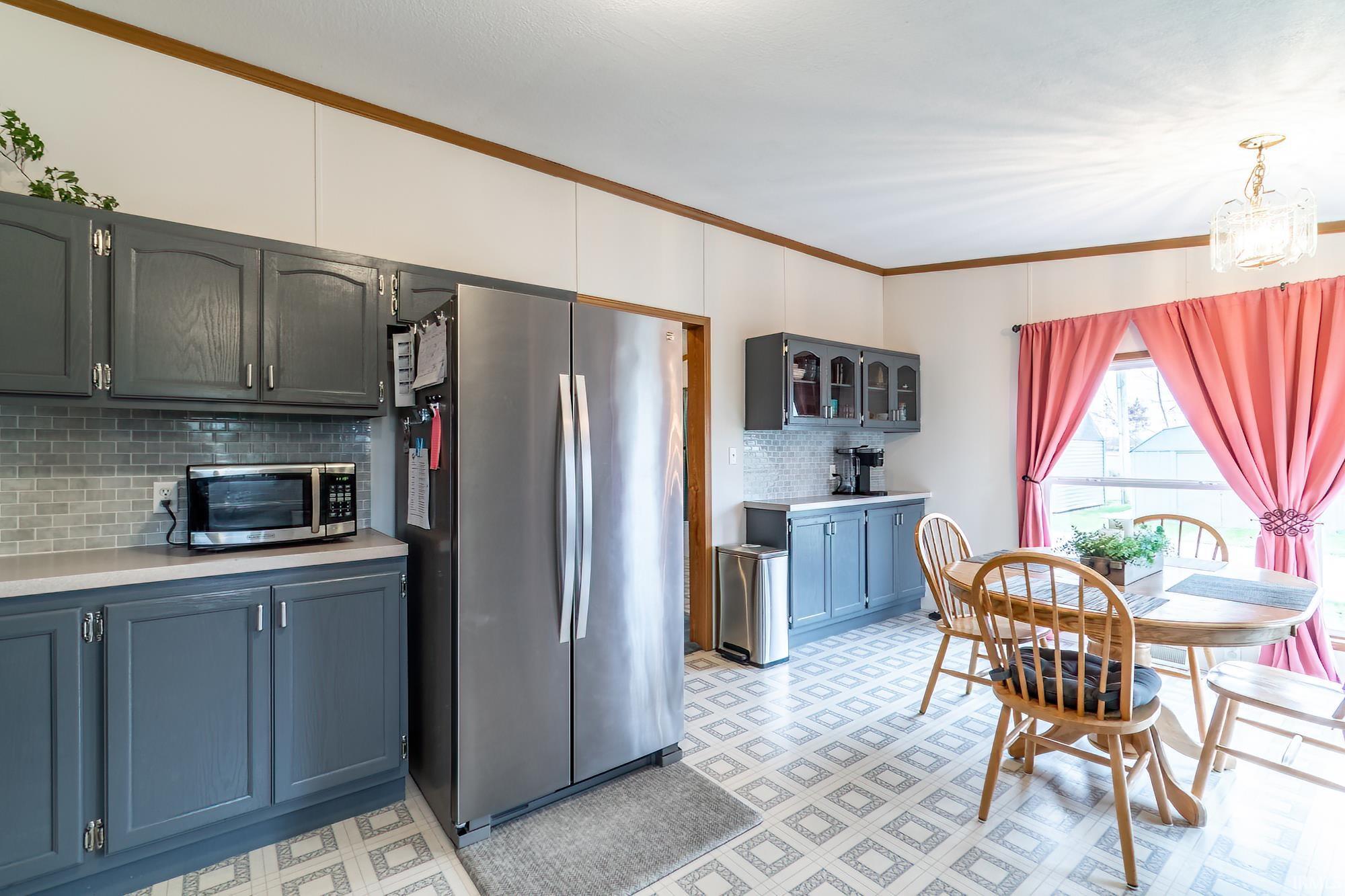 Kitchen with light floors, light countertops, stainless steel appliances, crown molding, and backsplash