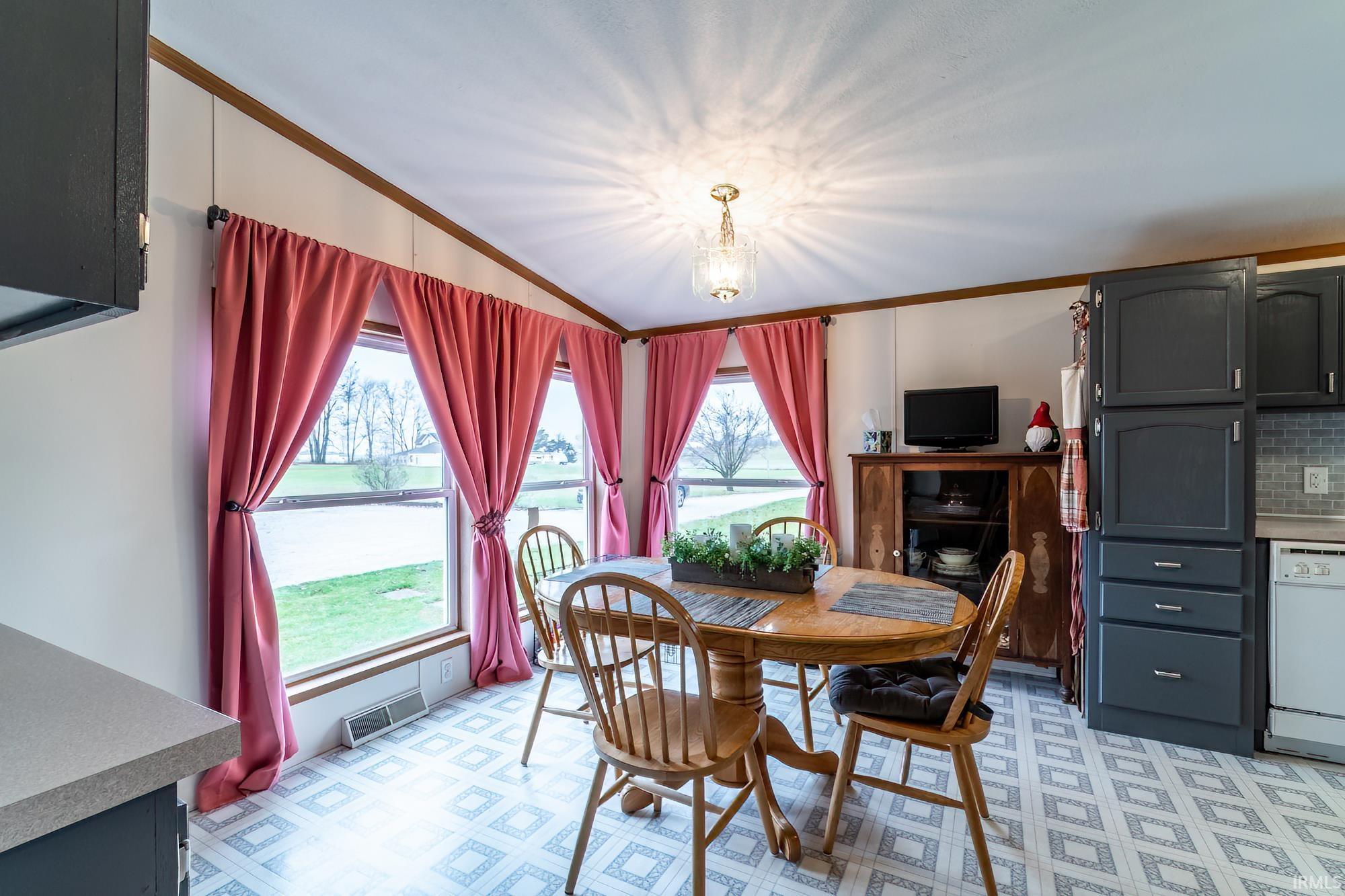Dining area with crown molding, lofted ceiling, and a chandelier