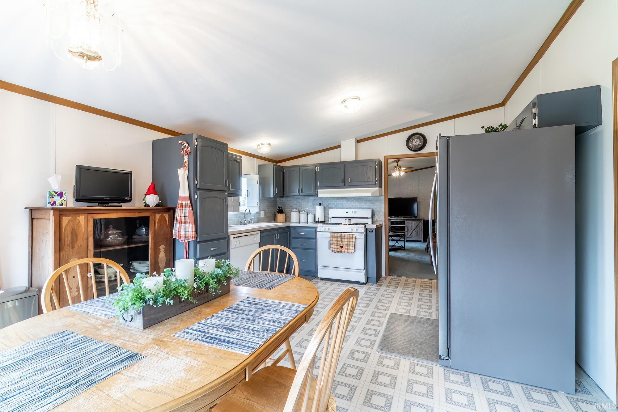Dining room featuring vaulted ceiling, ornamental molding, and light floors