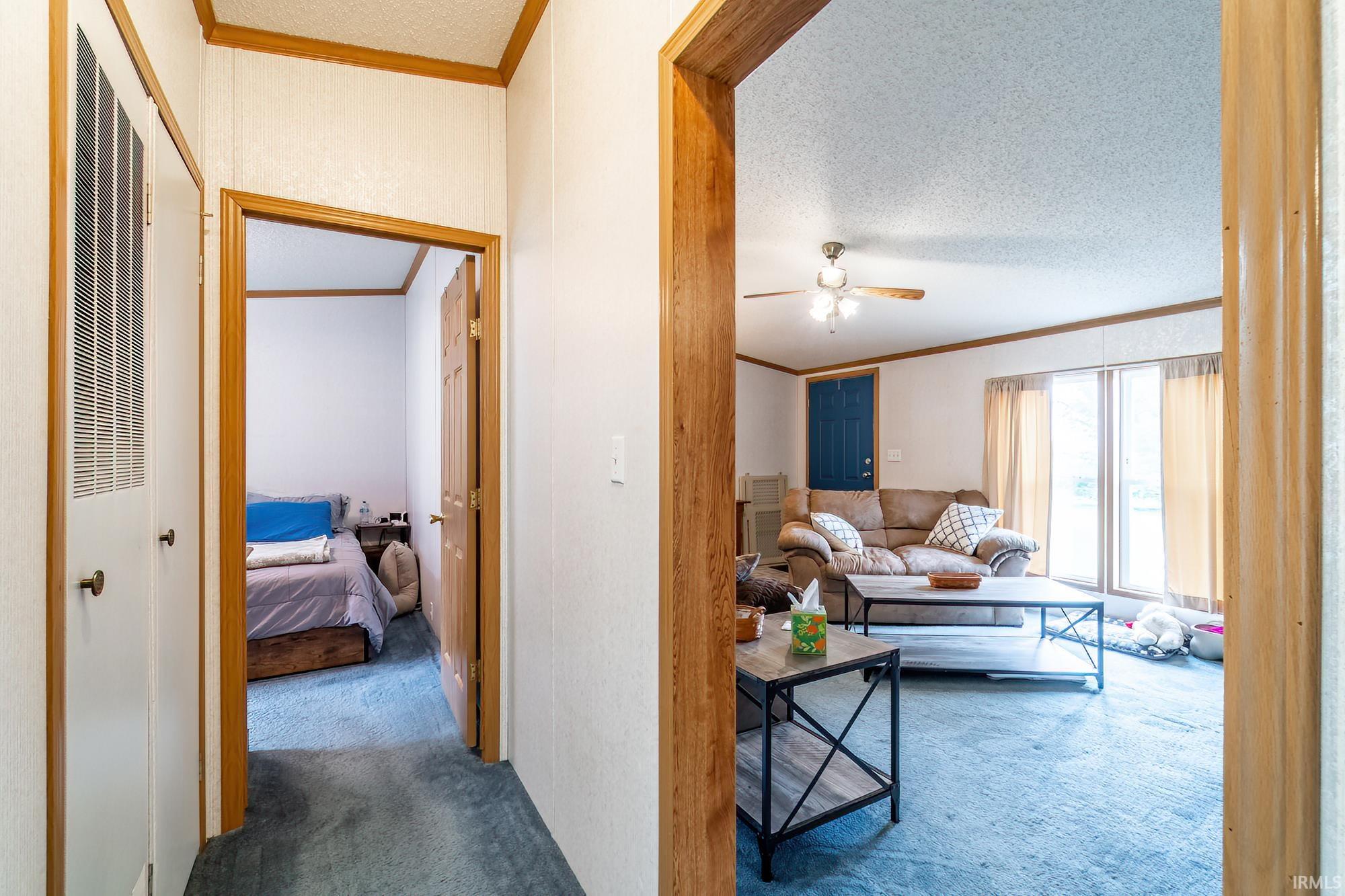 Corridor with ornamental molding, carpet, and a textured ceiling