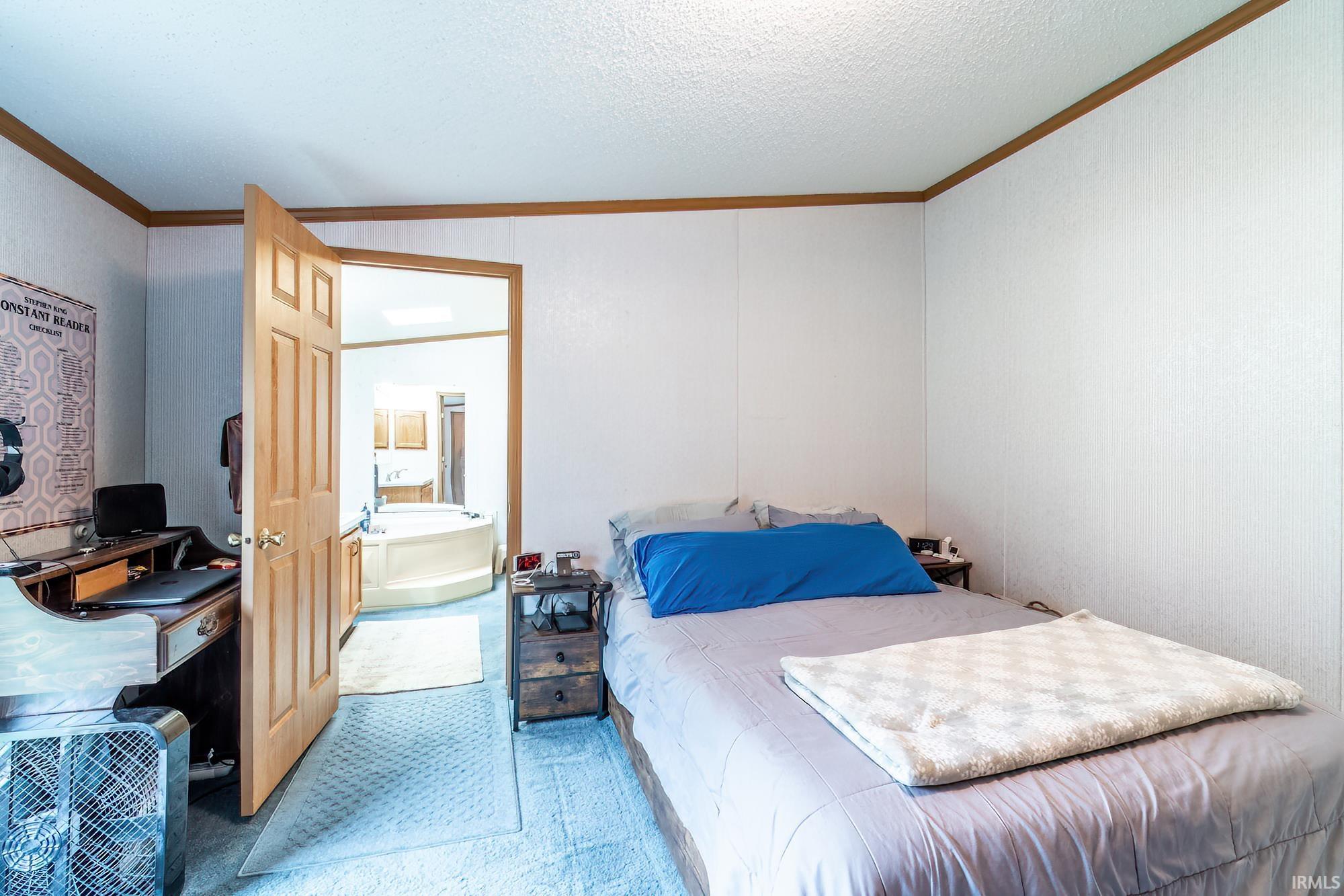 Carpeted bedroom featuring crown molding and a textured ceiling