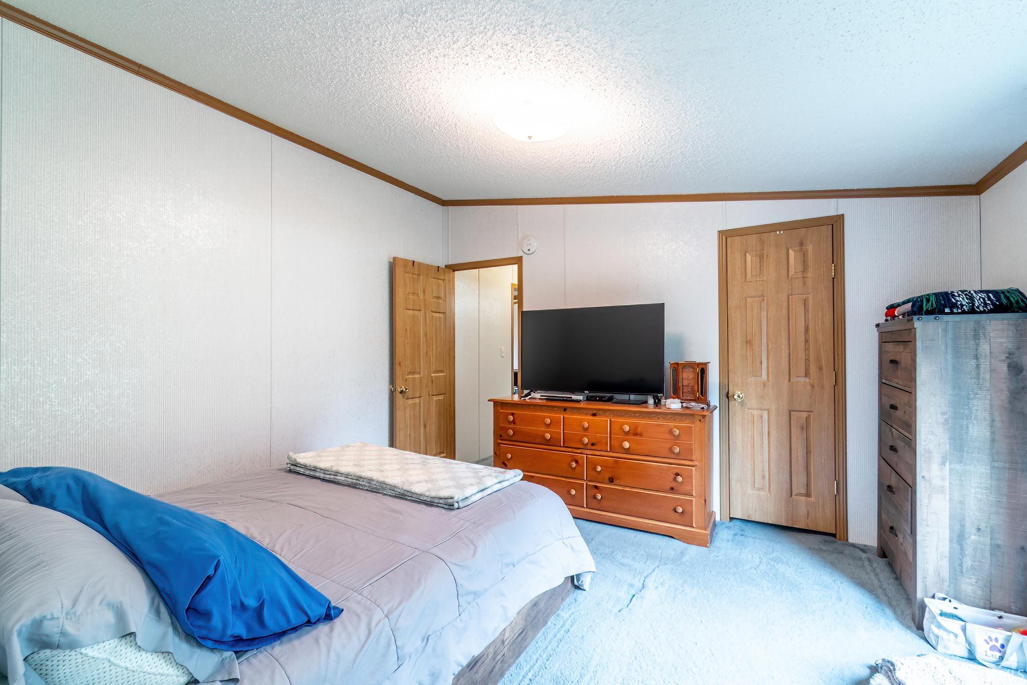 Bedroom featuring ornamental molding, carpet, a textured ceiling, and vaulted ceiling