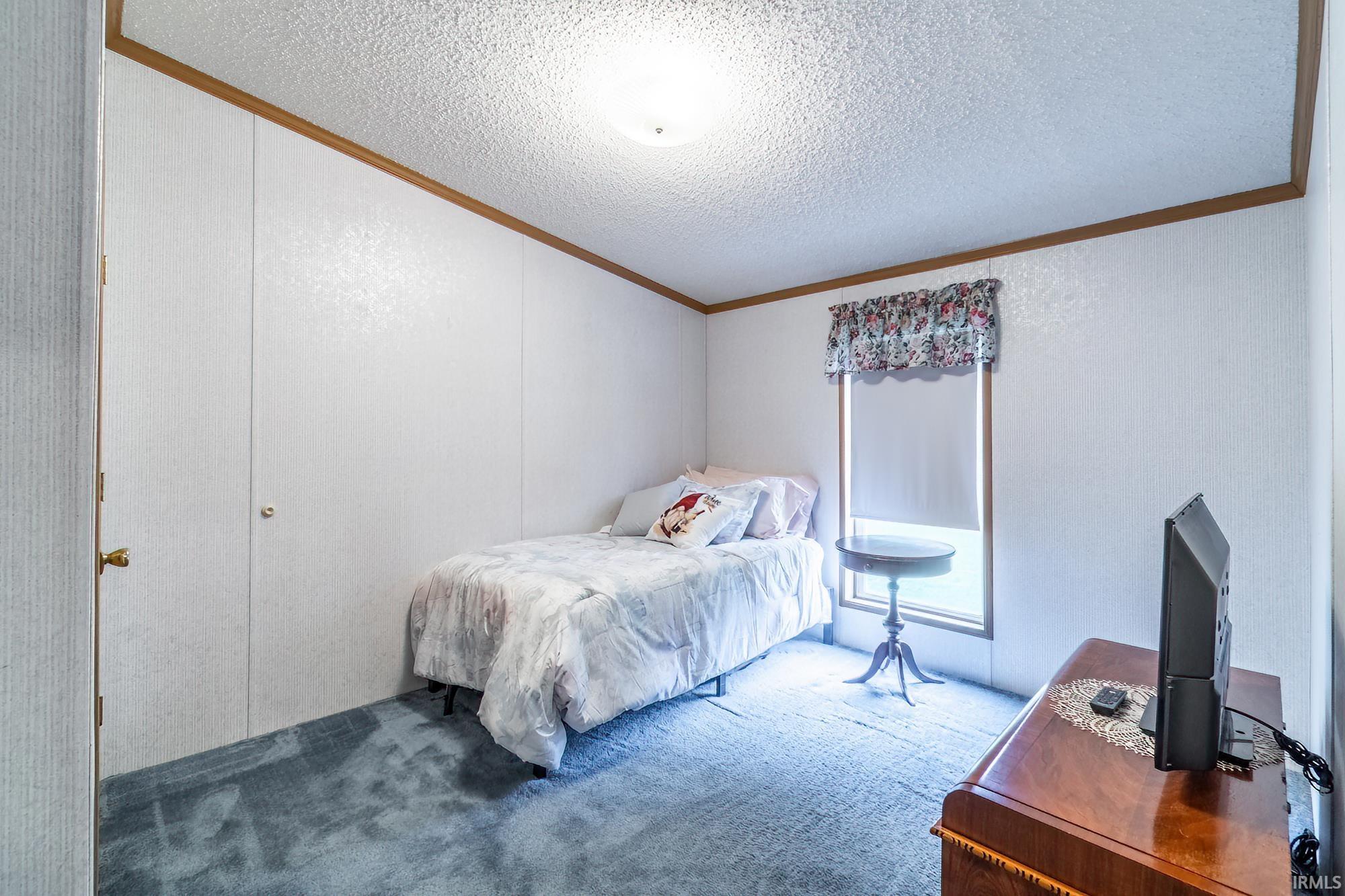 Bedroom featuring carpet flooring, crown molding, and a textured ceiling