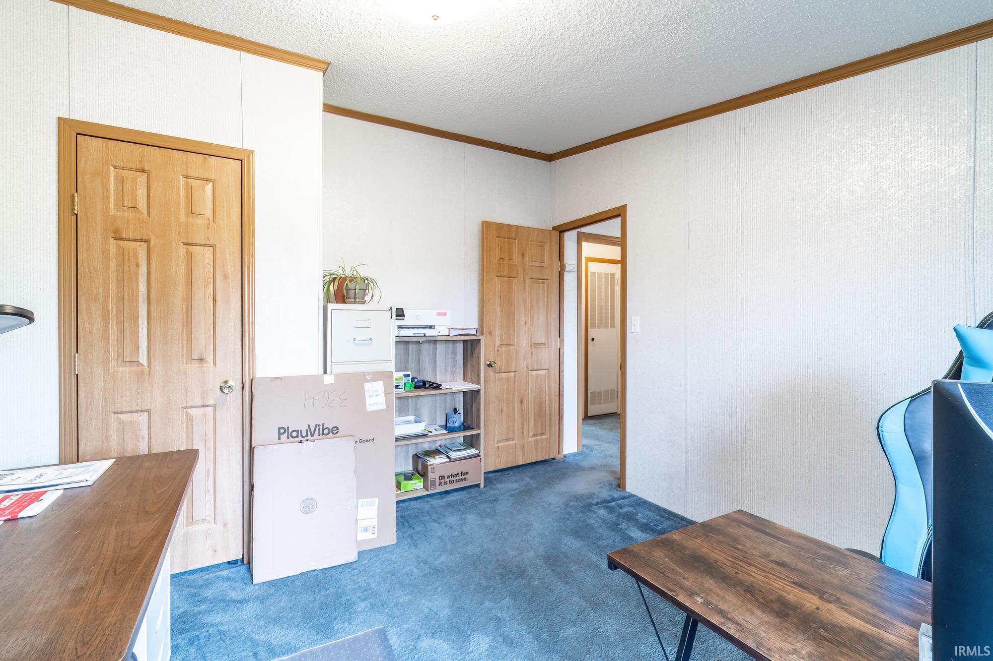 Office space featuring ornamental molding, dark colored carpet, and a textured ceiling