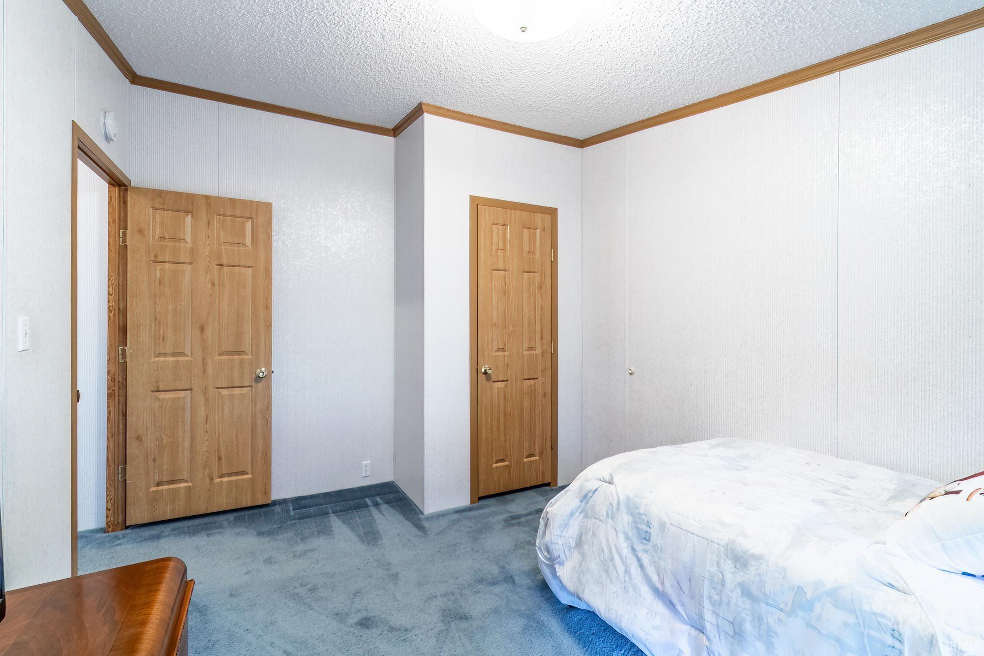 Bedroom featuring crown molding, carpet flooring, and a textured ceiling