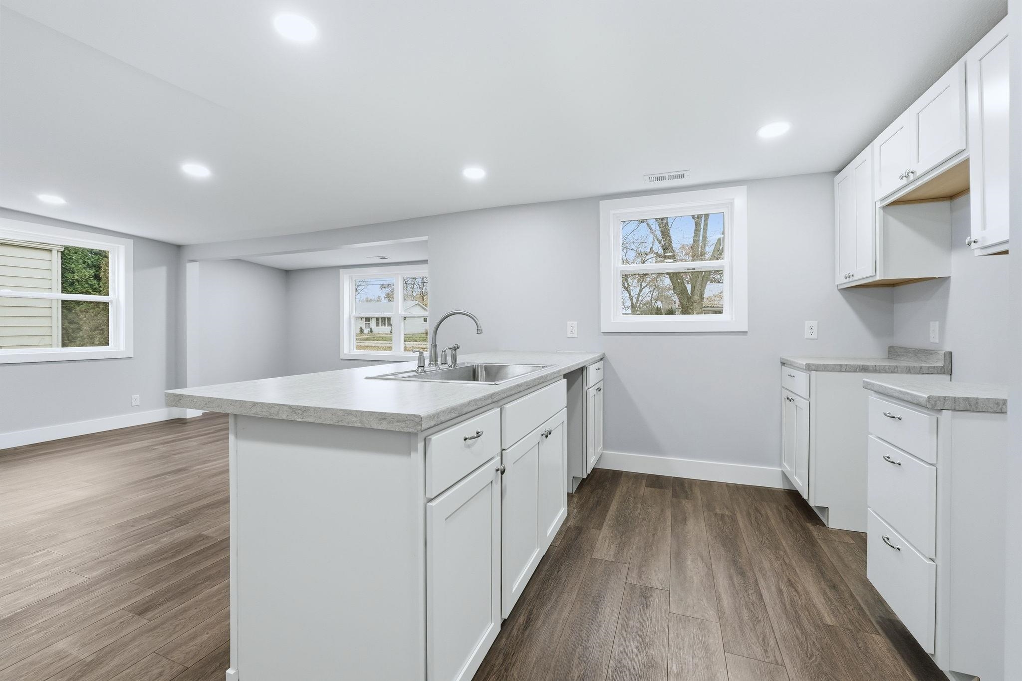 Kitchen with a peninsula, white cabinetry, light countertops, dark wood-style floors, and recessed lighting