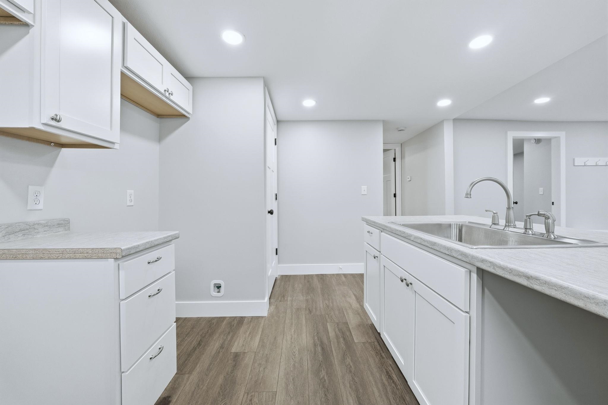 Kitchen featuring white cabinets, light countertops, dark wood-style floors, and recessed lighting