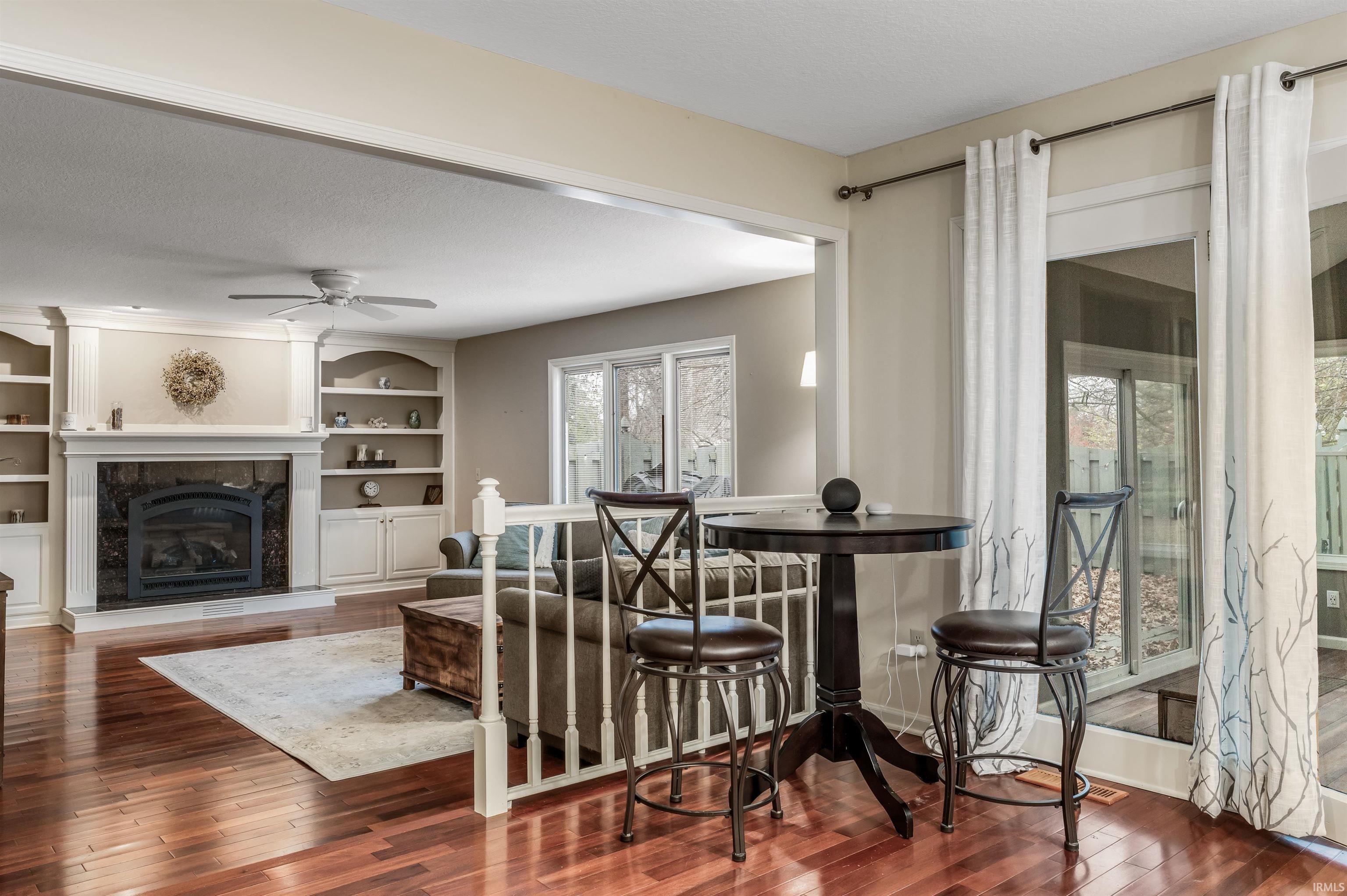 Dining space featuring dark wood-type flooring, a textured ceiling, a fireplace, built in features, and a ceiling fan