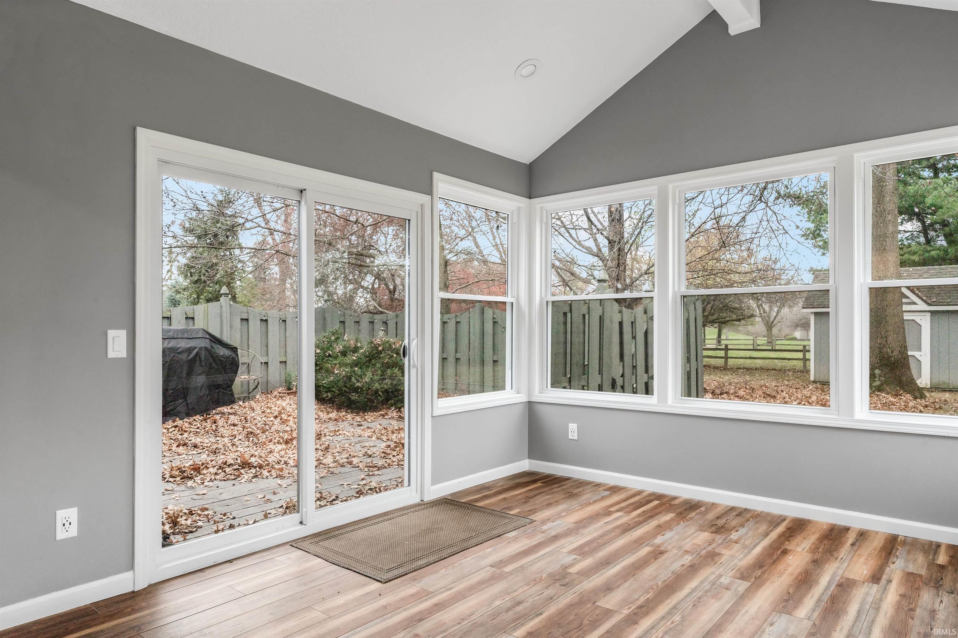 Unfurnished sunroom featuring lofted ceiling and wood finished floors