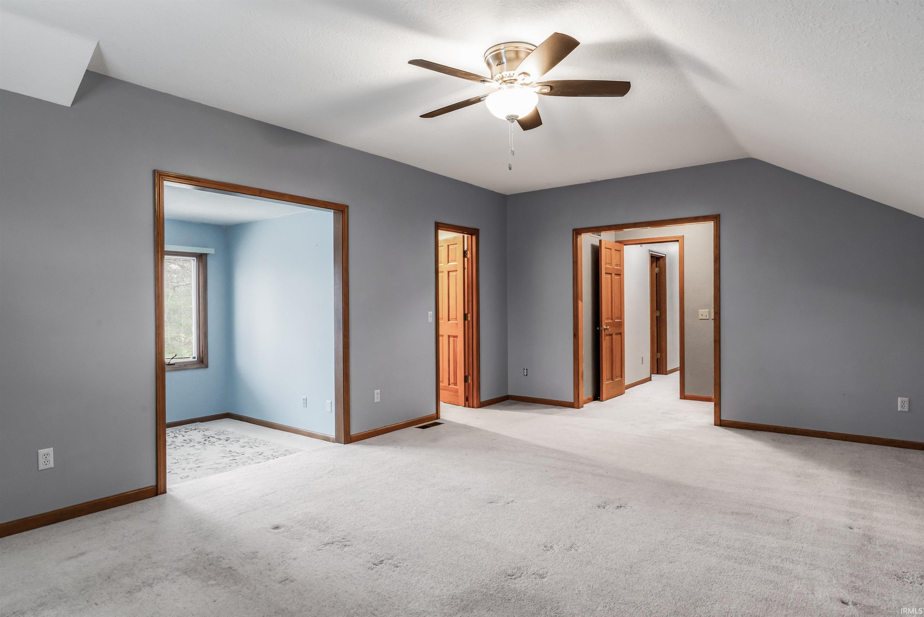Unfurnished bedroom with carpet flooring, a ceiling fan, and vaulted ceiling