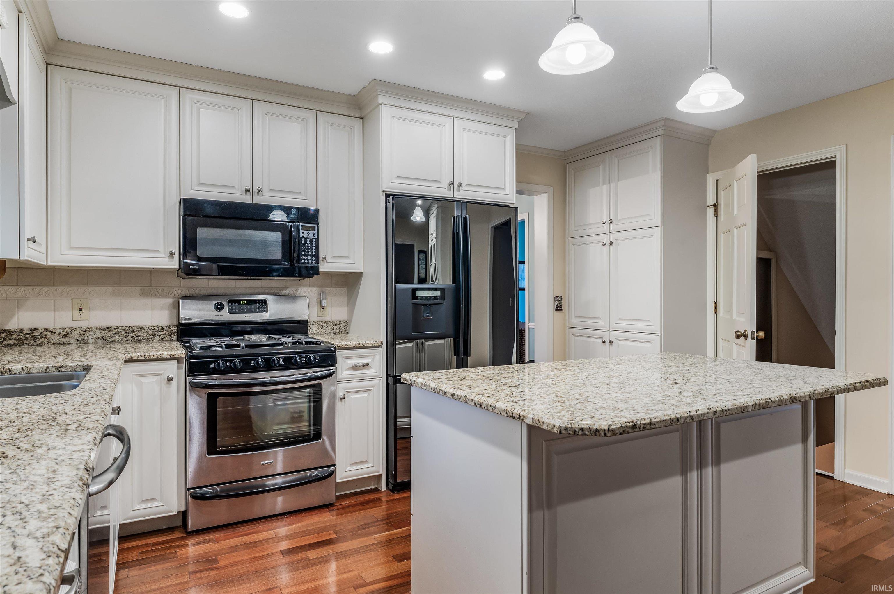 Kitchen featuring stainless steel appliances, white cabinetry, light stone countertops, and recessed lighting