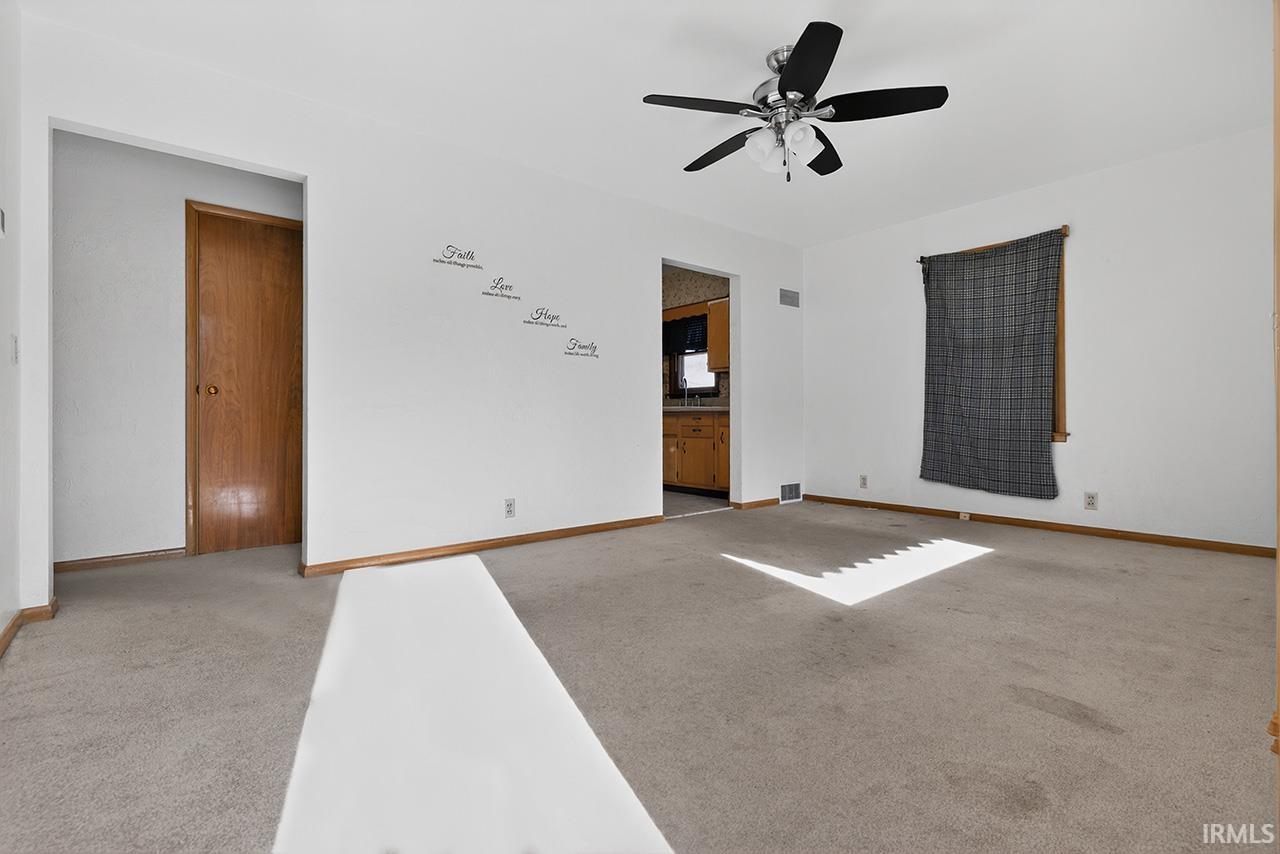 Unfurnished room with light colored carpet and a ceiling fan