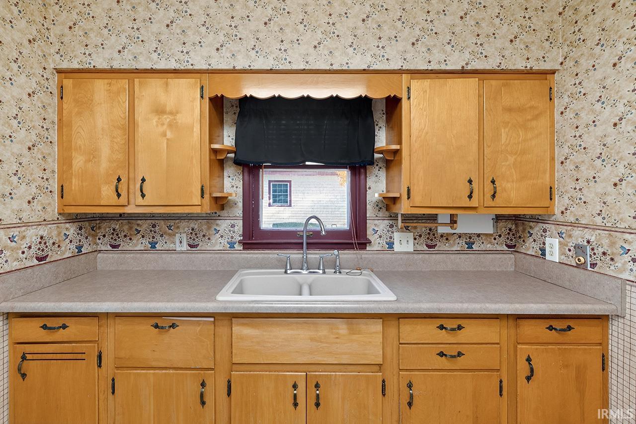 Kitchen featuring wallpapered walls, open shelves, and light countertops