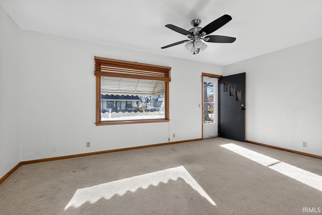 Carpeted spare room featuring plenty of natural light and a ceiling fan