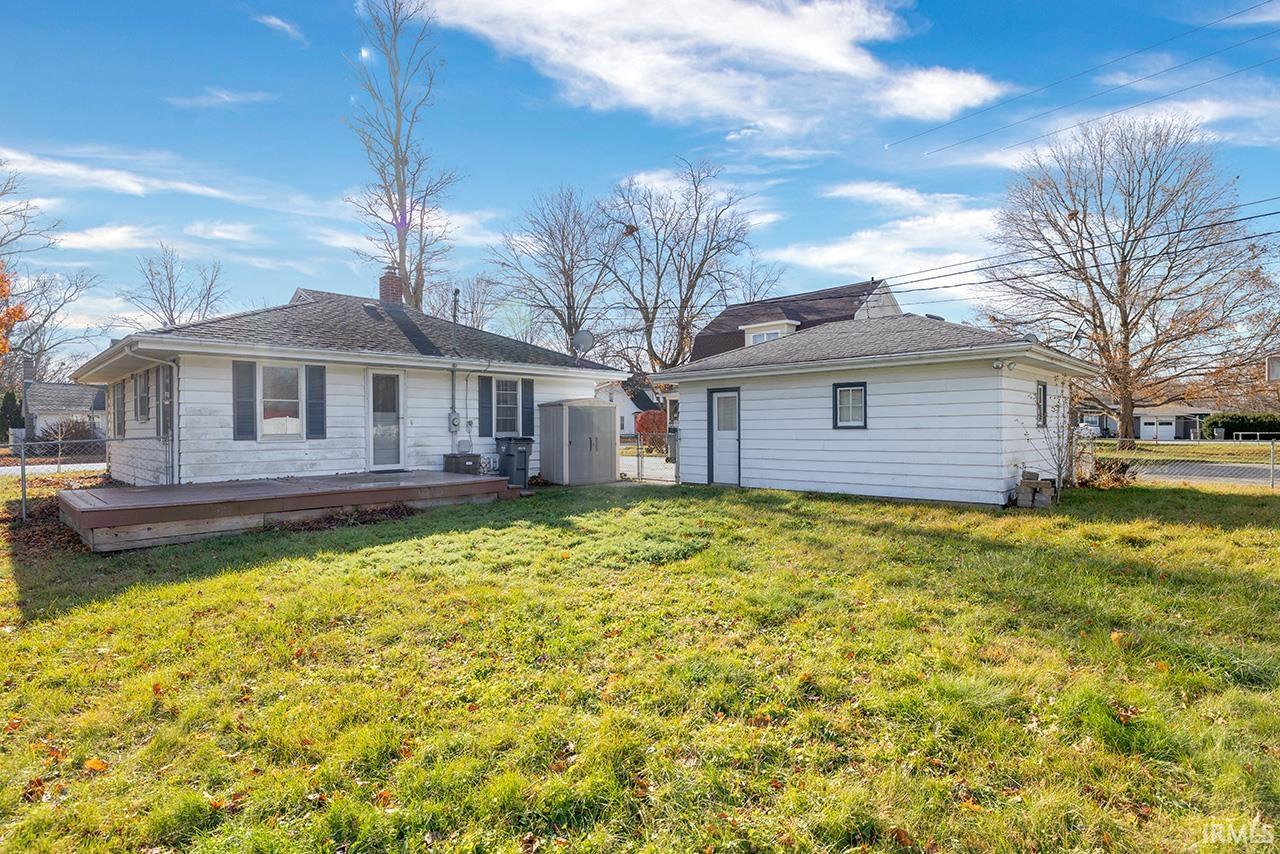 Rear view of house featuring a lawn, a deck, and a chimney