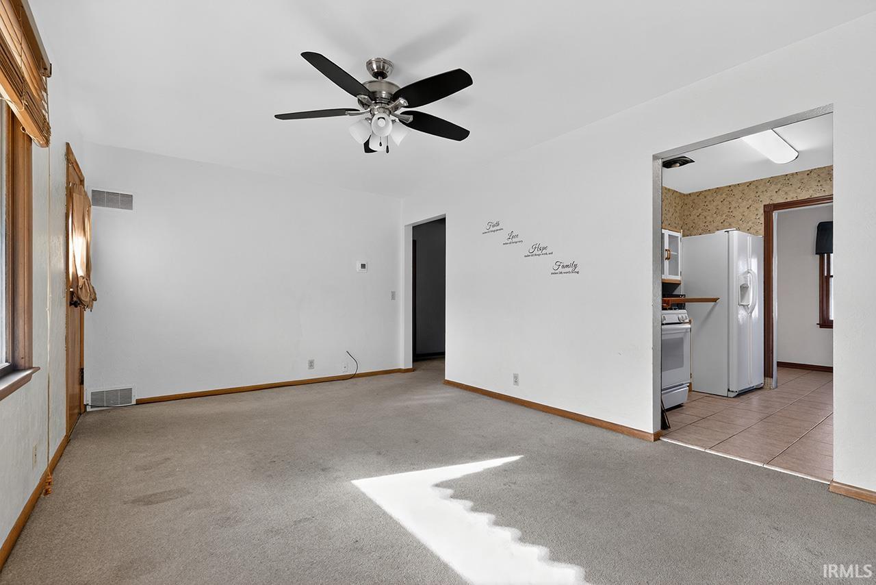 Unfurnished room with light colored carpet, ceiling fan, and wallpapered walls