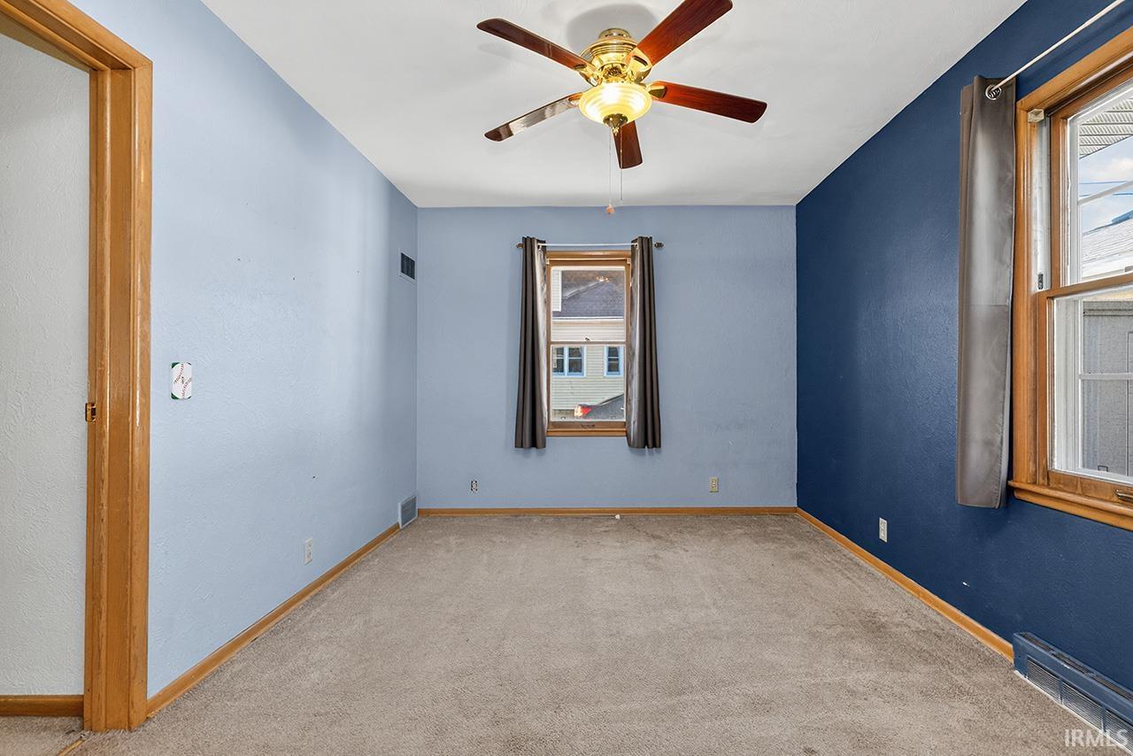 Carpeted spare room with a ceiling fan and baseboards