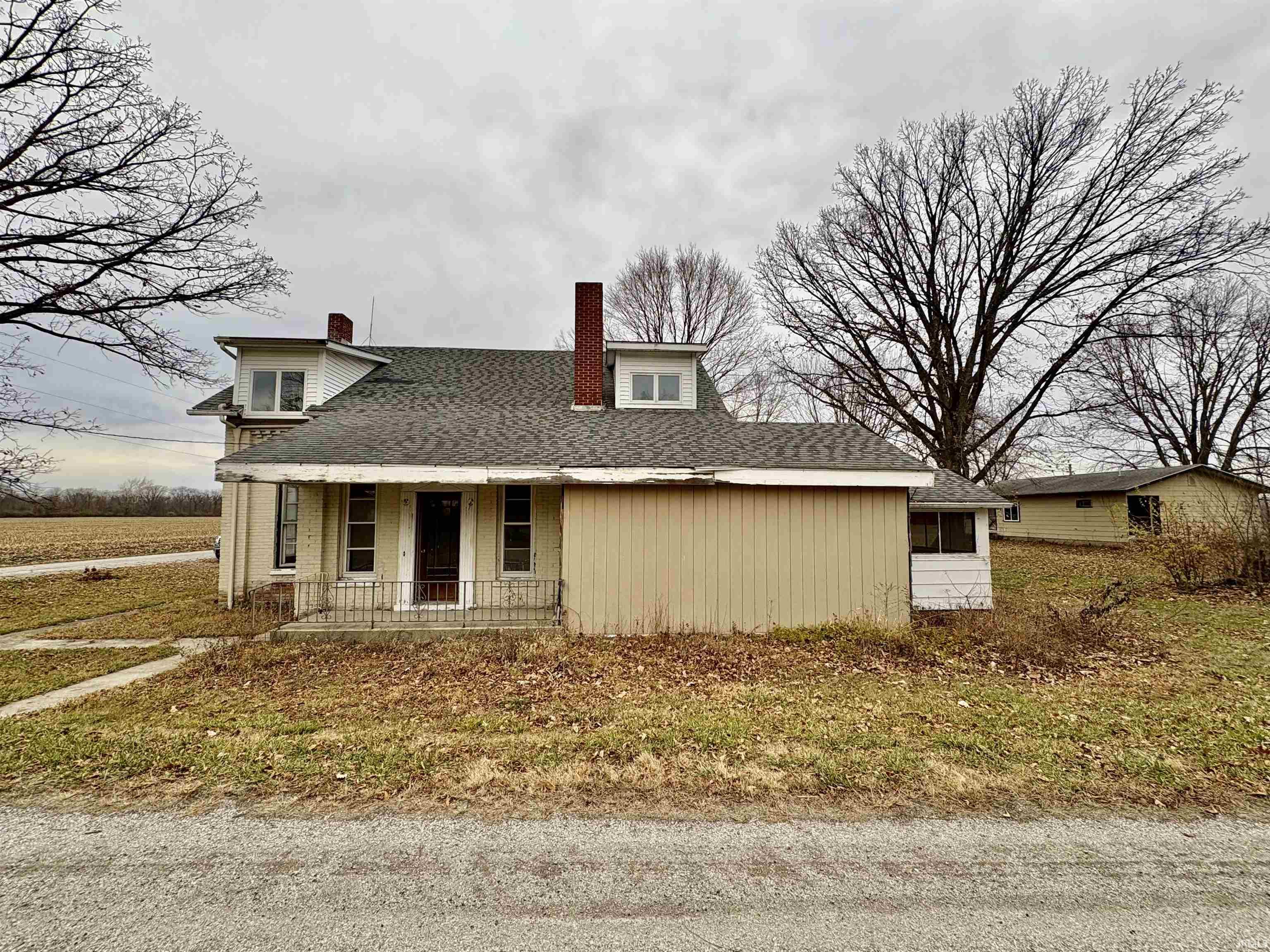 View of front of home featuring a chimney, roof with shingles, and covered porch