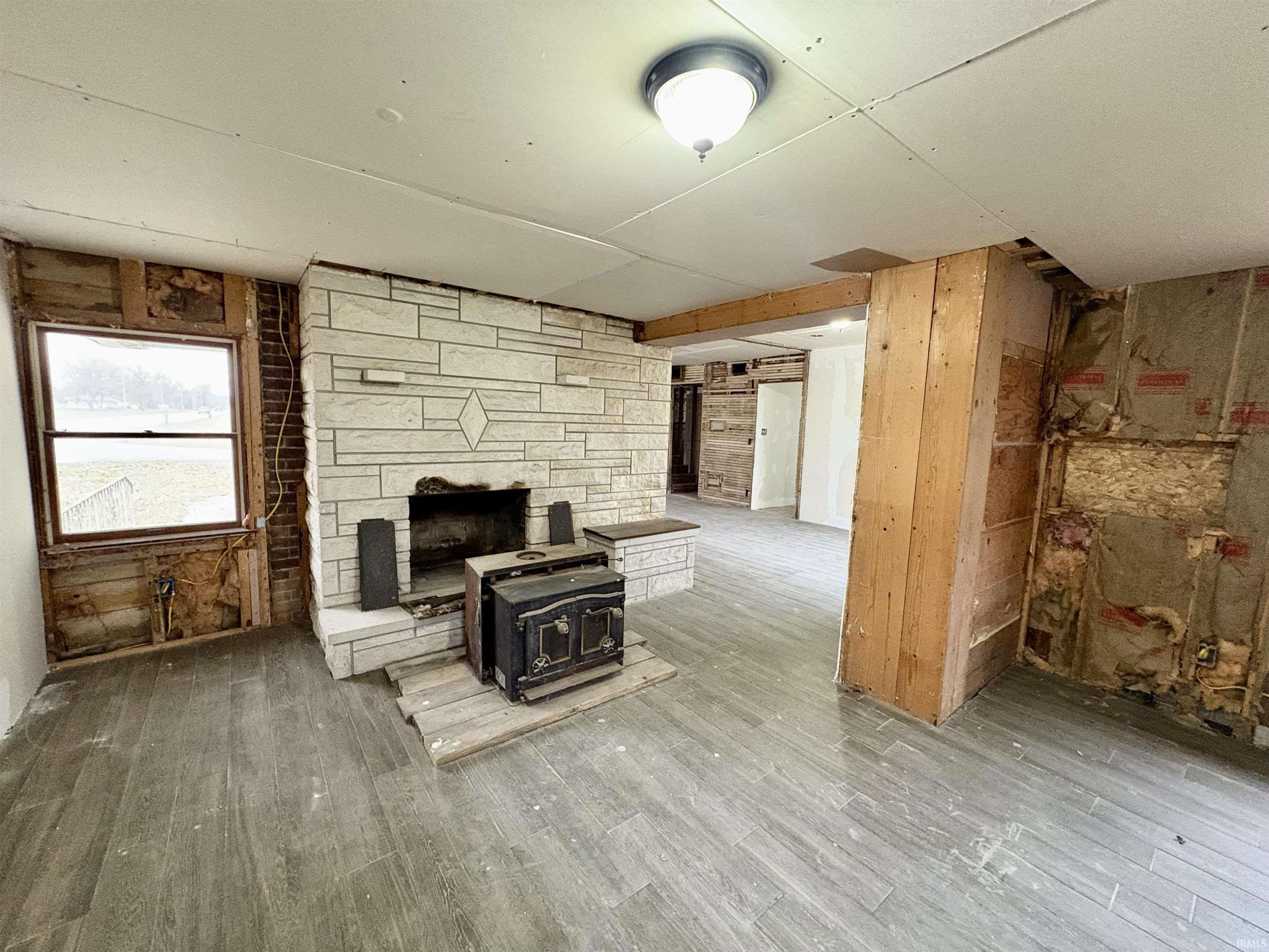 Unfurnished living room with wood finished floors, wood walls, and a wood stove