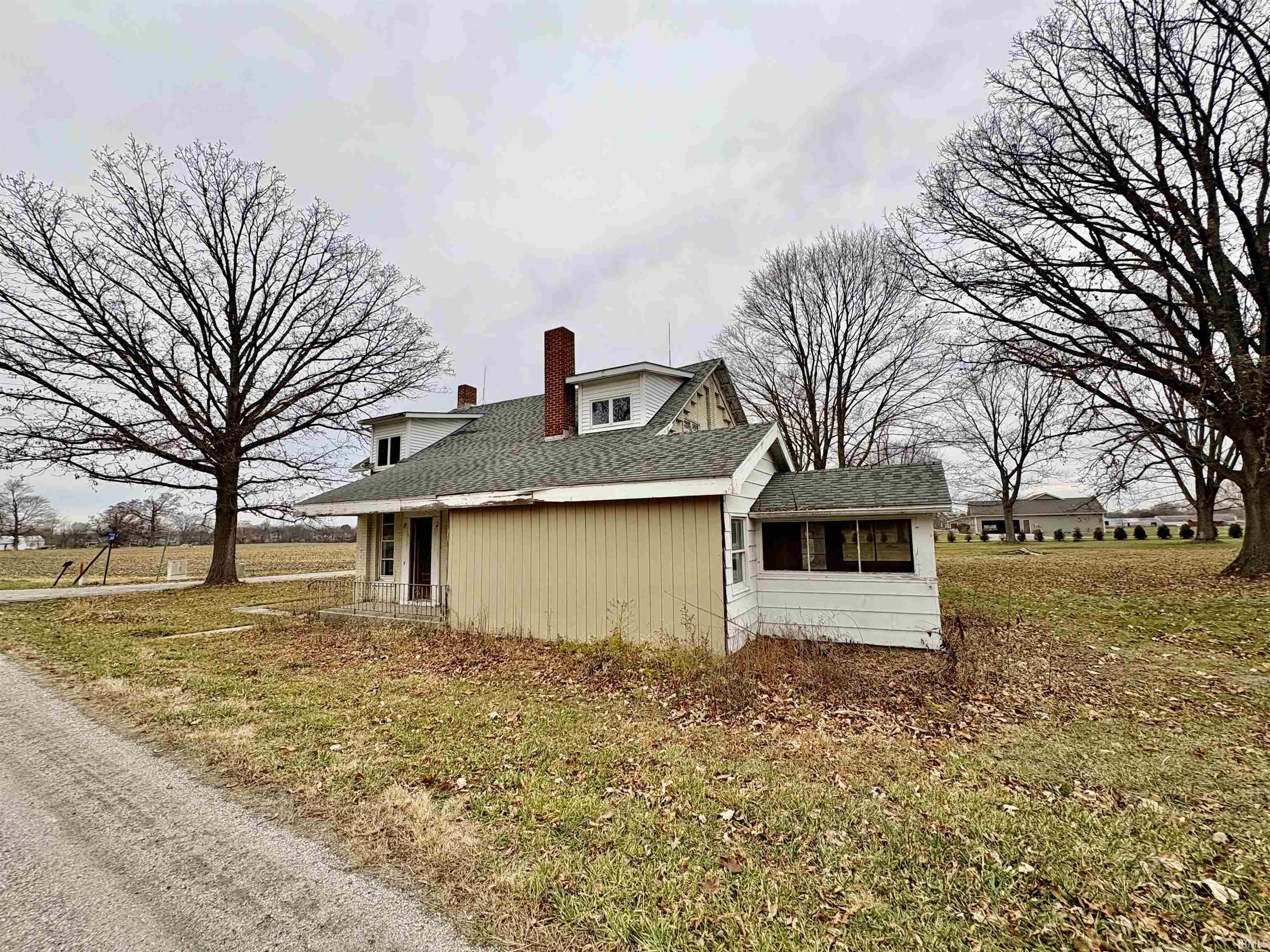 View of home's exterior featuring a chimney, a yard, a shingled roof, and a sunroom